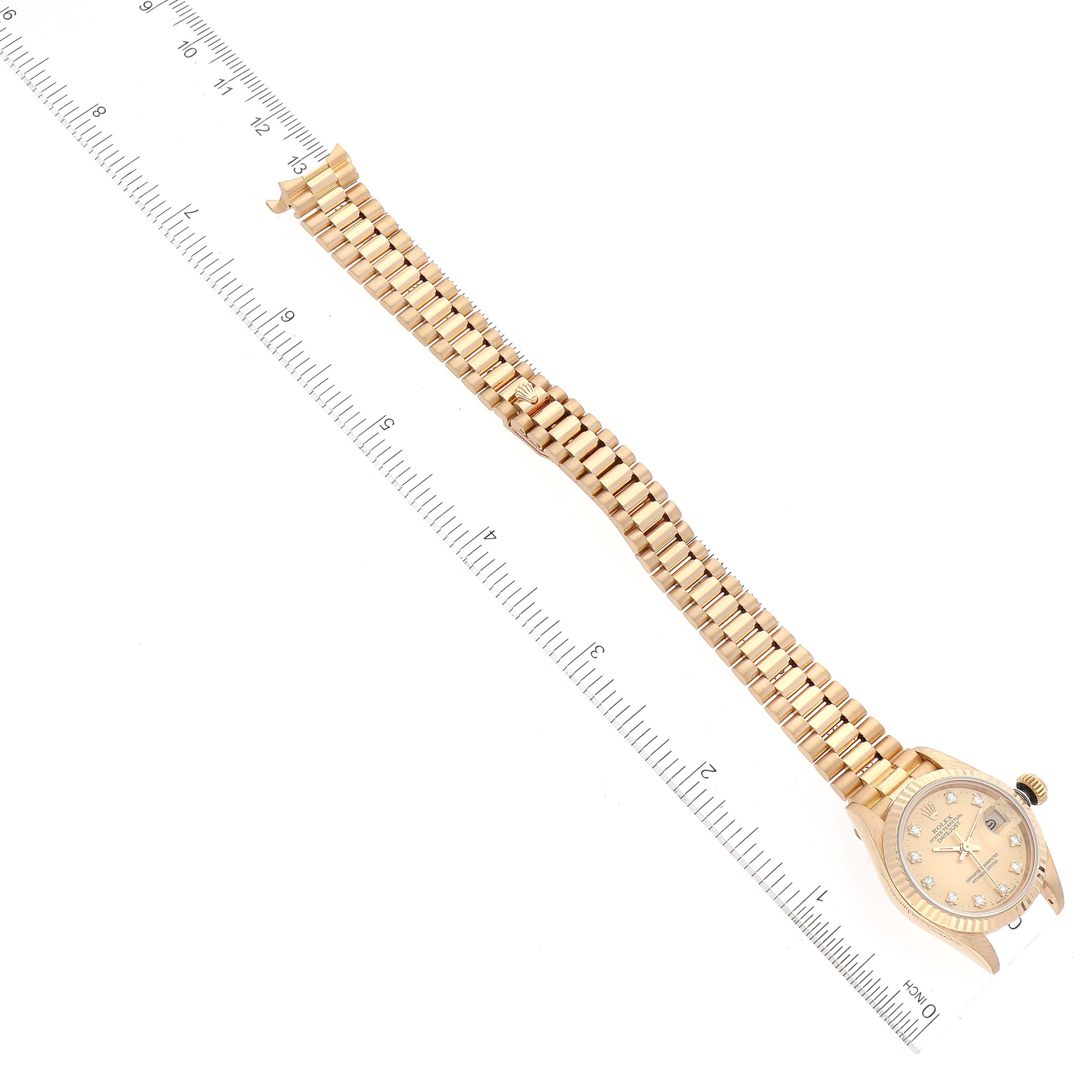 This image shows a Rolex President 69178 Women
s Yellow Gold Champagne Dial 69178 Women
s Yellow Gold Champagne Dial model watch laid flat with its bracelet and dial visible, alongside a ruler for scale.