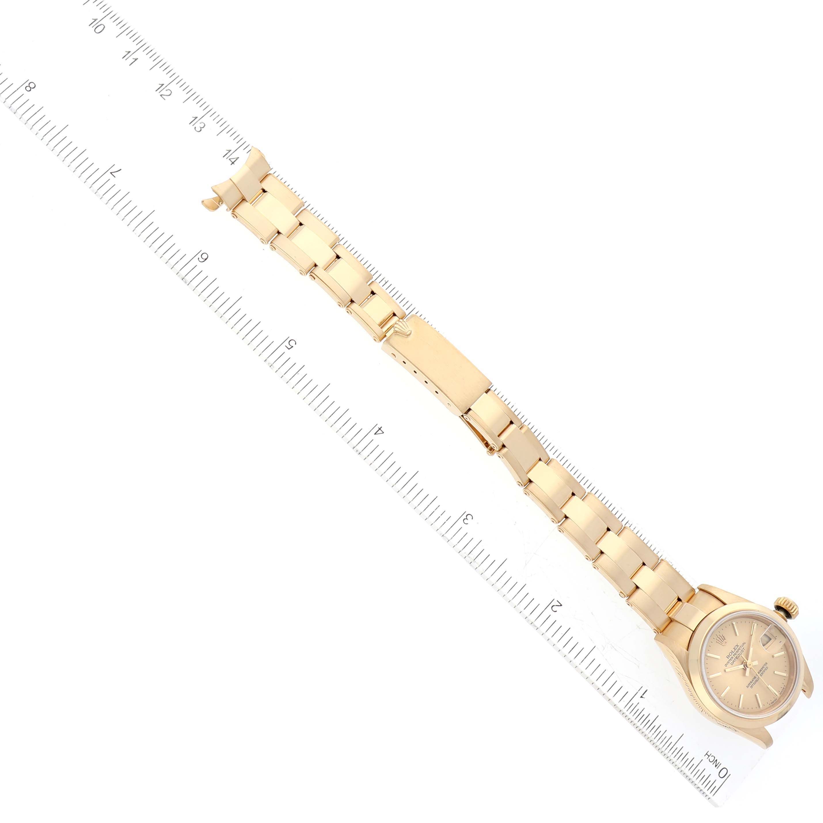 The image shows the President model Rolex watch laid flat with a focus on its band beside a ruler for scale.