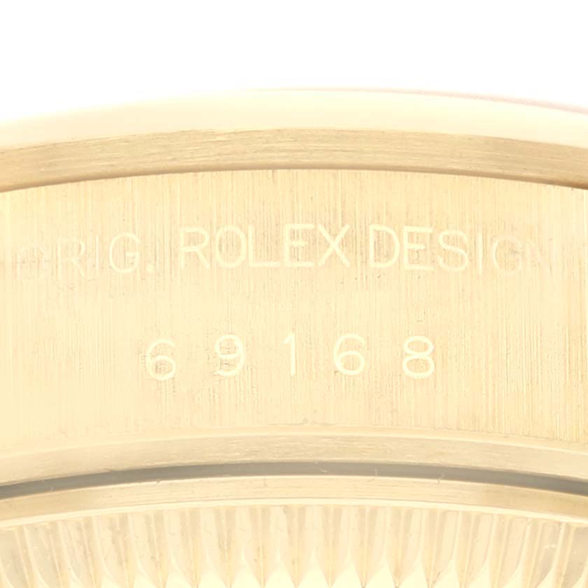 The image shows the engravings on the edge of the Rolex President 69168 Women
s Yellow Gold Champagne Dial 69168 Women
s Yellow Gold Champagne Dial model, including the design numbers and text "ROLEX DESIGN".