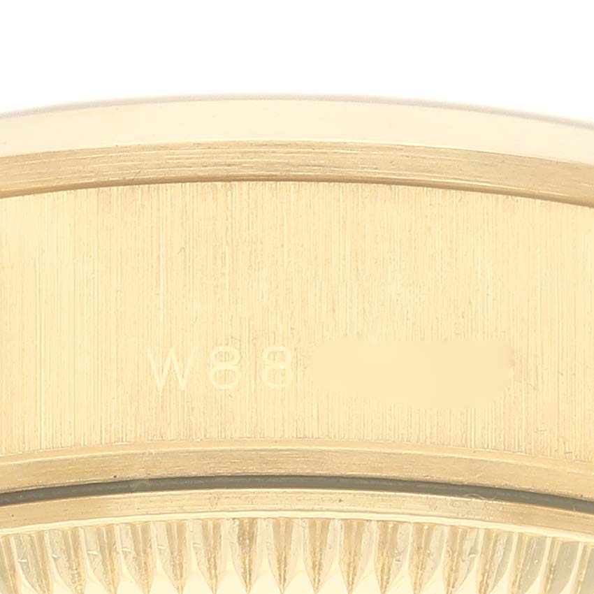 The image shows a close-up of the side of a Rolex President 69168 Women
s Yellow Gold Champagne Dial 69168 Women
s Yellow Gold Champagne Dial model watch, focusing on its serial number and the fluted bezel.