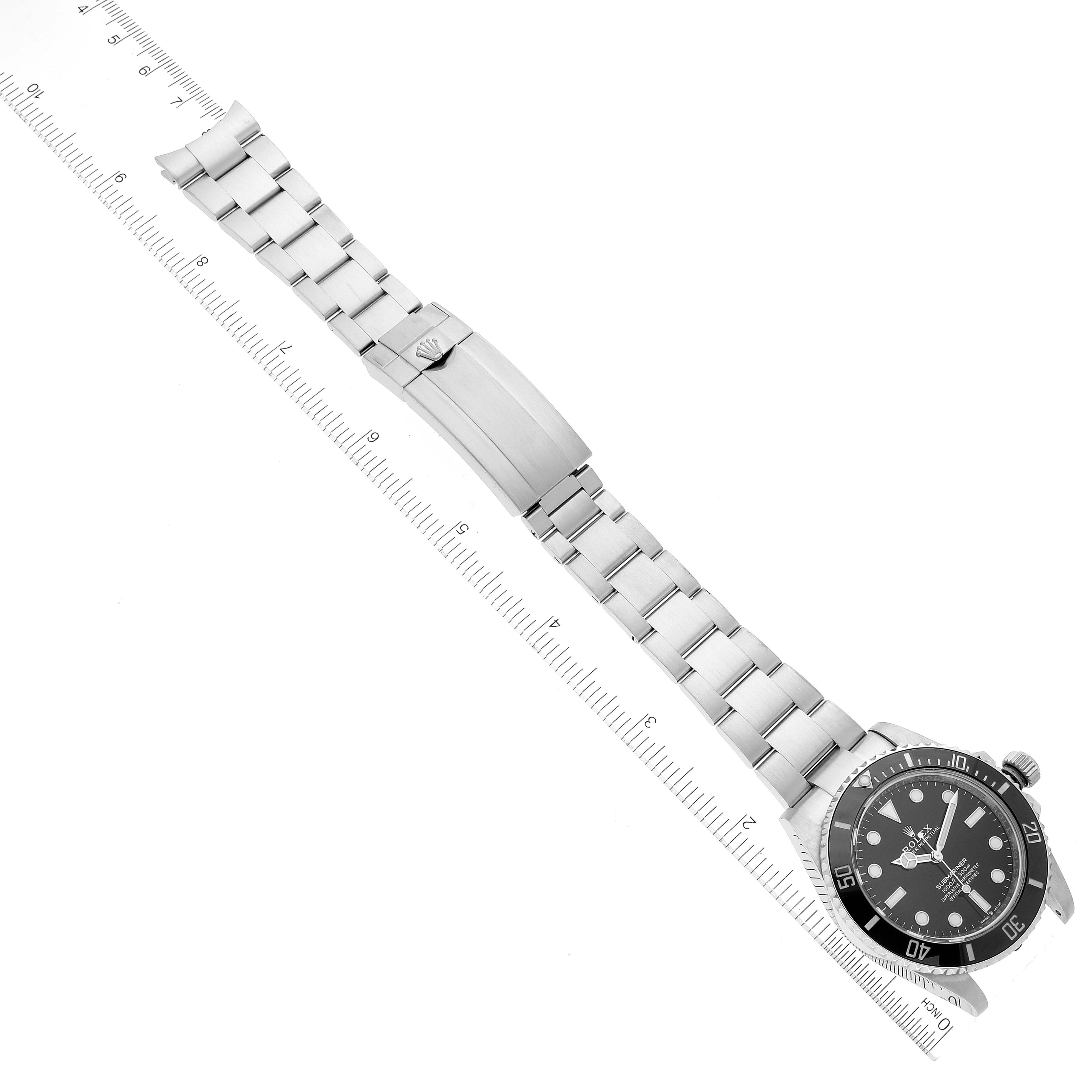 The Rolex Submariner 124060 Men
s Stainless Steel Black Dial 124060 Men
s Stainless Steel Black Dial watch is shown at a top-down angle, displaying the face, bezel, and full bracelet with a clasp, alongside a ruler.