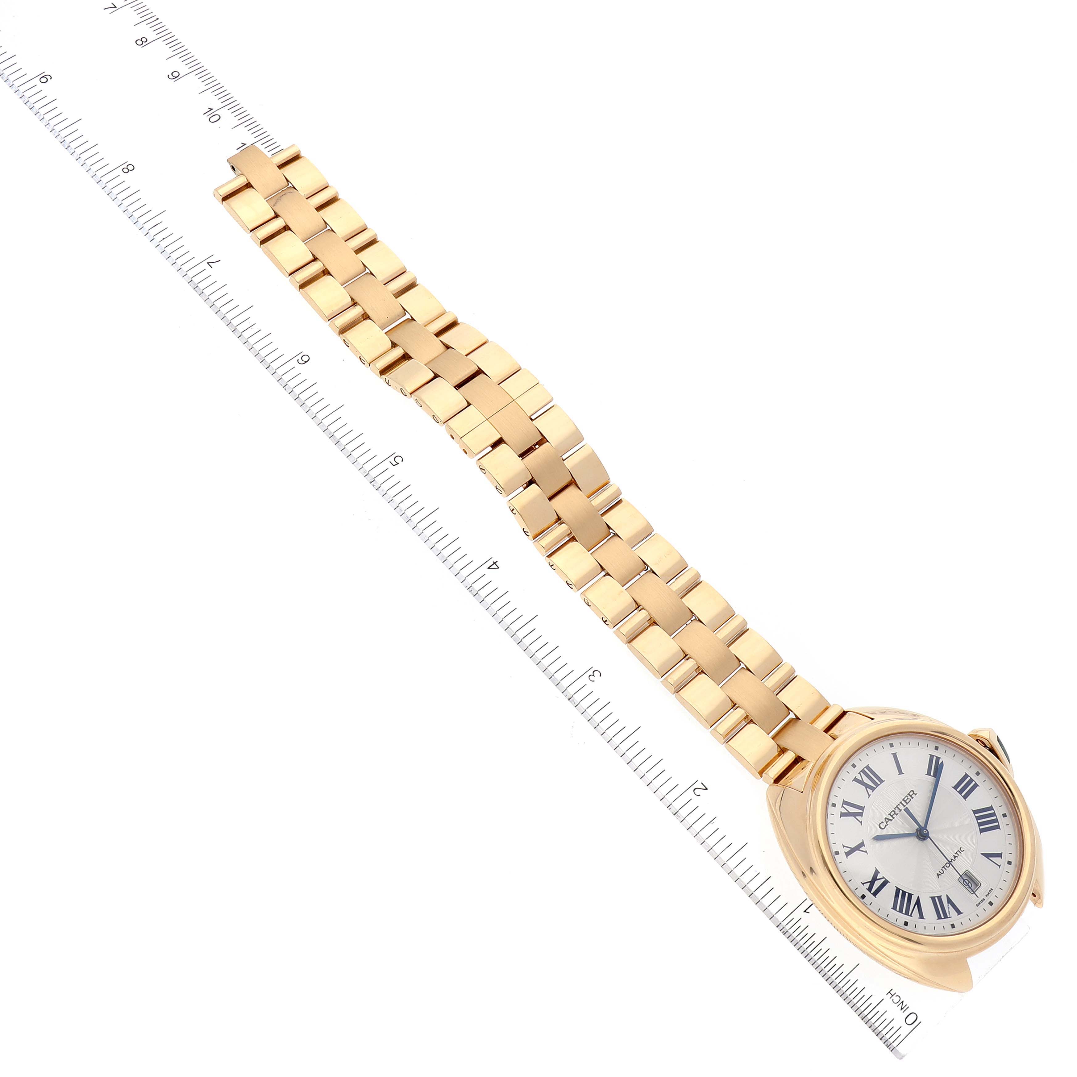 The Cartier Cle WGCL0003 Men's Yellow Gold Blue Dial WGCL0003 Men's Yellow Gold Blue Dial model watch is photographed from an angled top view, showing its dial, case, and bracelet next to a ruler.