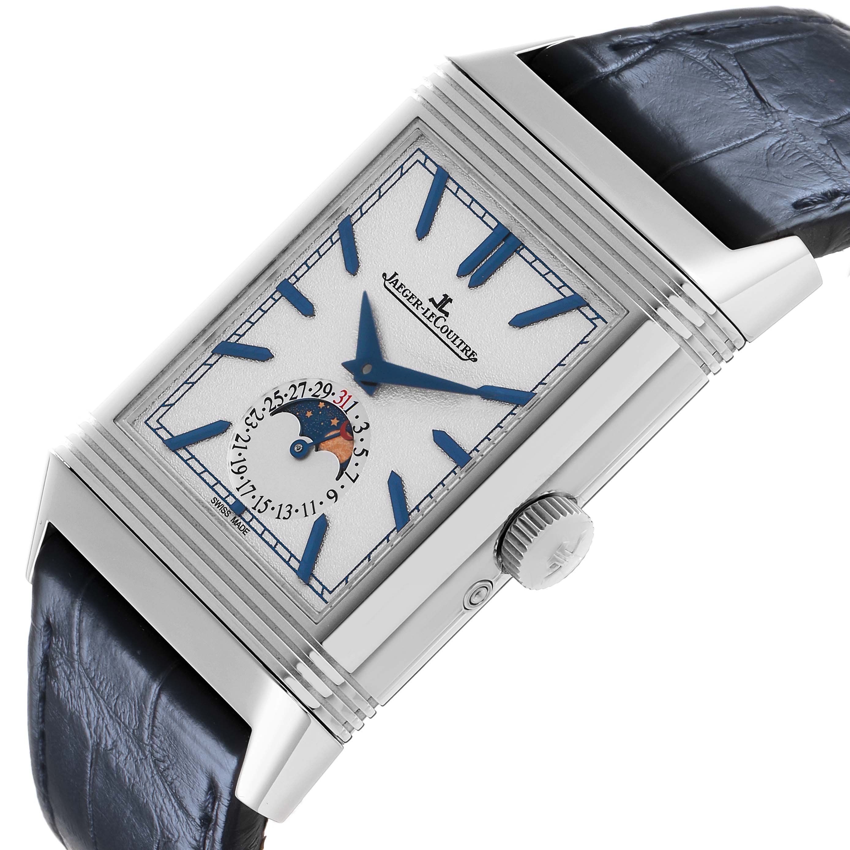 The Jaeger-LeCoultre Reverso watch is shown at an angled view, displaying the face with blue hands, indices, a moon phase, and date indicator.