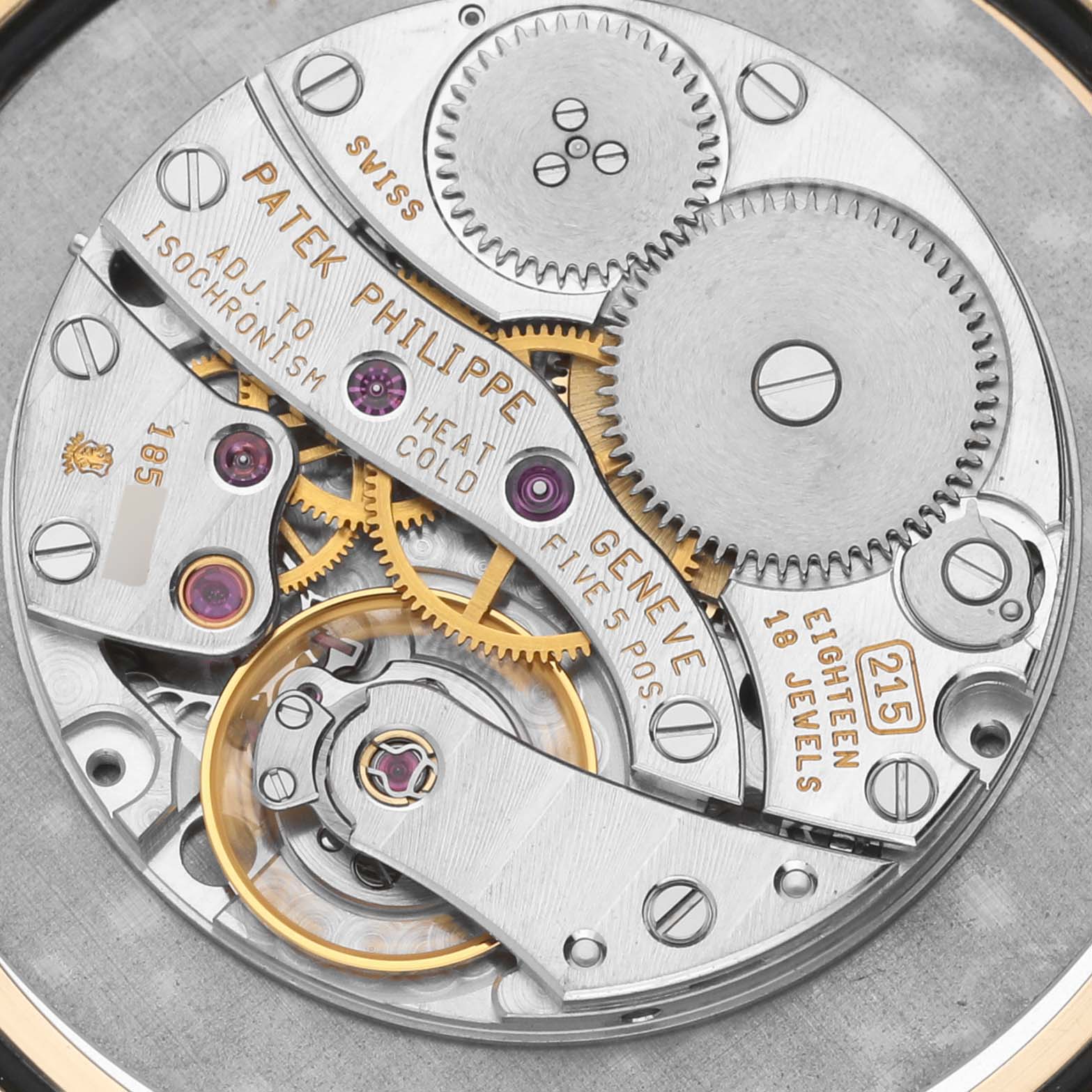 This image shows the intricate inner mechanism of the Patek Philippe Calatrava 3919J Men's Yellow Gold White Dial 3919J Men's Yellow Gold White Dial watch, viewed from the back, displaying gears and engravings.