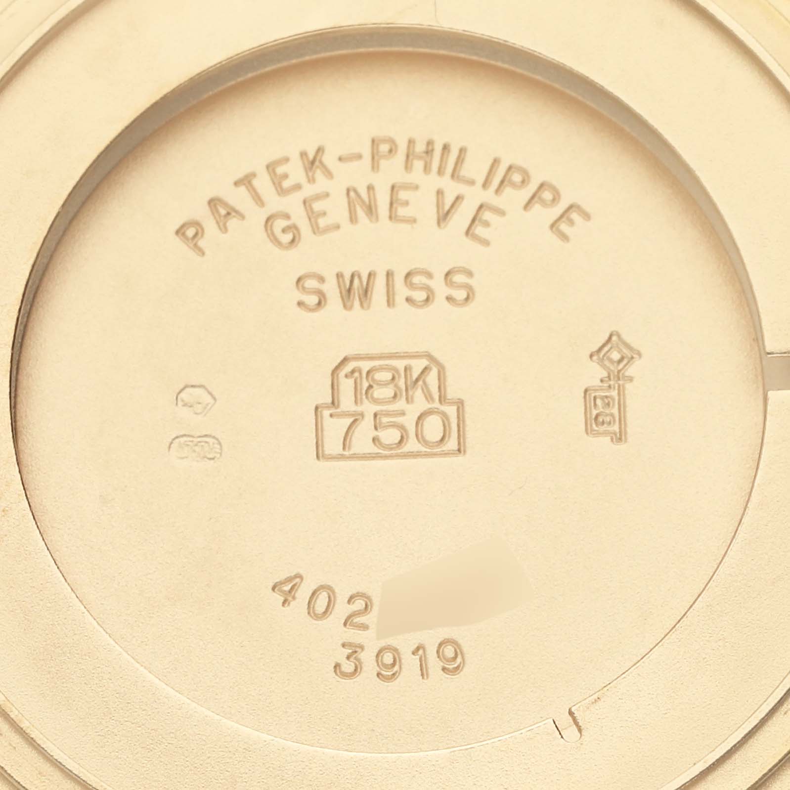 The image shows the interior case back of the Patek Philippe Calatrava 3919J Men's Yellow Gold White Dial 3919J Men's Yellow Gold White Dial, highlighting the brand markings and gold purity stamp (18K).
