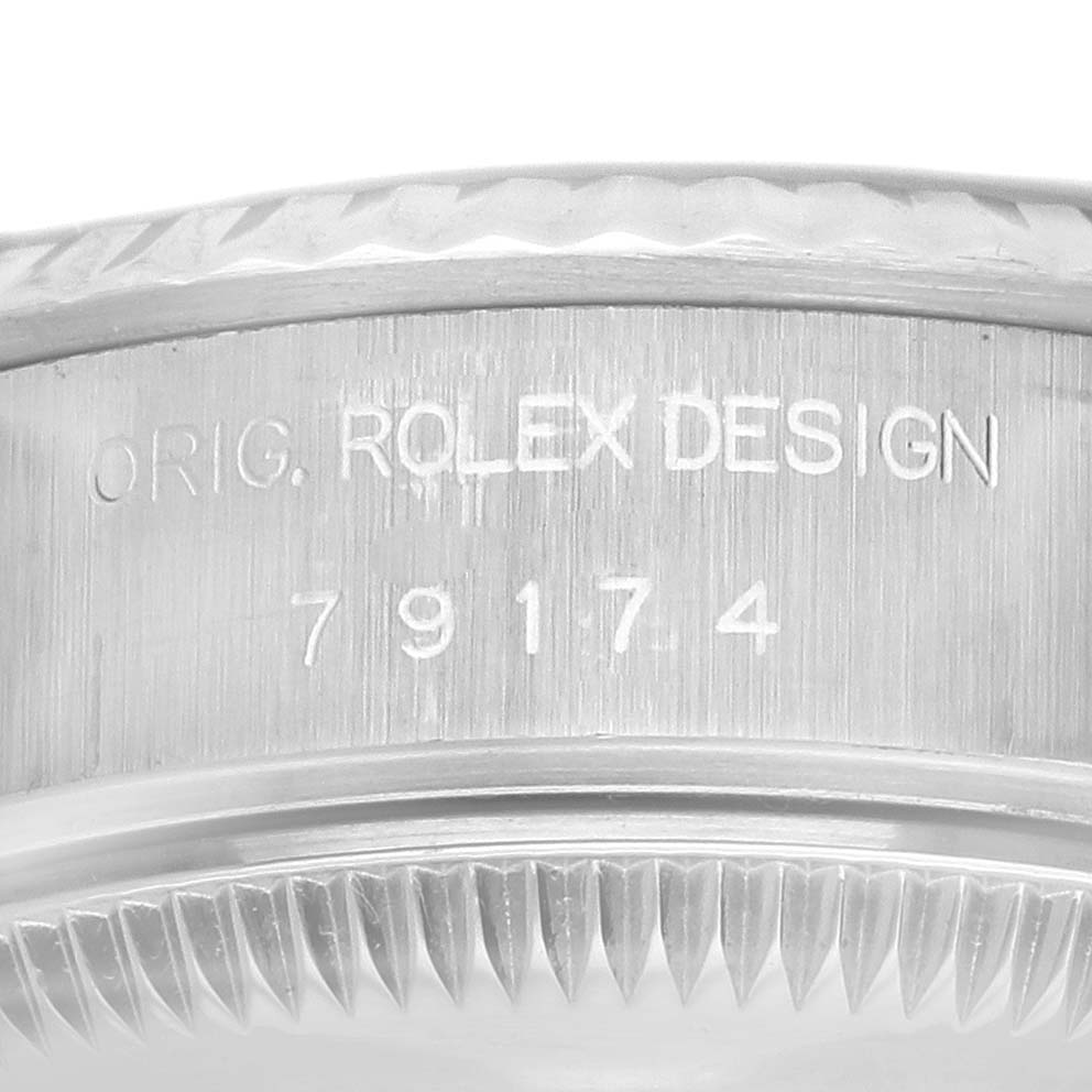 The image shows the side of a Rolex Datejust 79174 Women's Stainless Steel Blue Dial 79174 Women's Stainless Steel Blue Dial watch case with "ORIG. ROLEX DESIGN" and model number 79174 engraved.