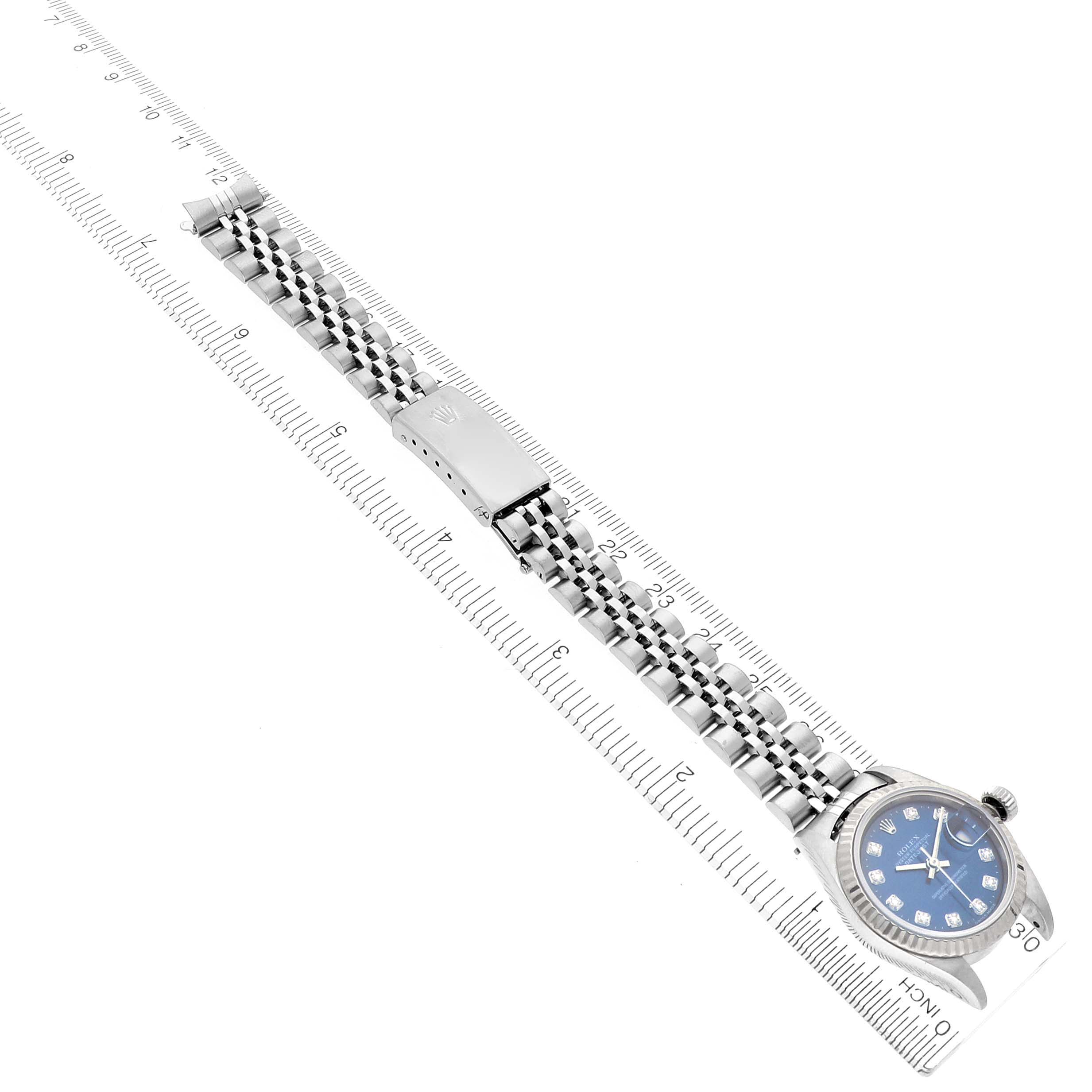 The Rolex Datejust 79174 Women's Stainless Steel Blue Dial 79174 Women's Stainless Steel Blue Dial watch is shown from a top-down angle, displaying the dial, bracelet, and clasp against a ruler background.