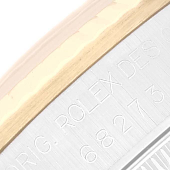 This close-up view of a Rolex Datejust 68273 Women's Steel and Gold (two tone) White Dial 68273 Women's Steel and Gold (two tone) White Dial watch shows part of the bezel and the engraved serial number on the case.
