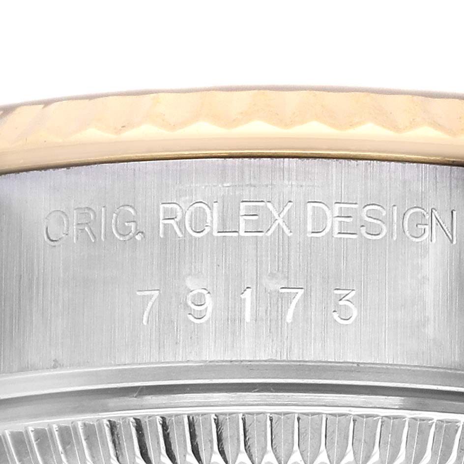 The image shows a close-up of the Rolex Datejust 79173 Women's Steel and Gold (two tone) Champagne Dial 79173 Women's Steel and Gold (two tone) Champagne Dial model's serial number engraving on the case's edge and fluted bezel.