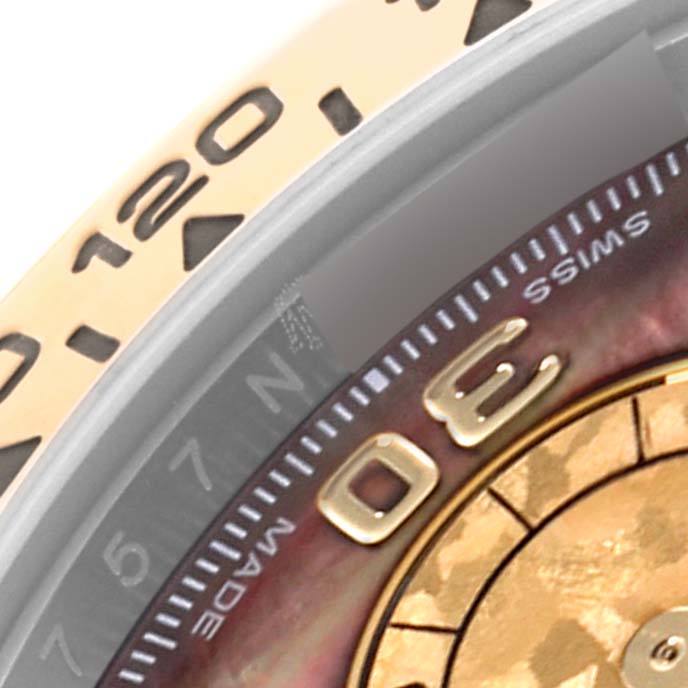 The image shows a close-up of the Rolex Daytona 116503 Men's Steel and Gold (two tone) Mother of Pearl Dial 116503 Men's Steel and Gold (two tone) Mother of Pearl Dial's bezel and part of the dial, highlighting details like the numerals.