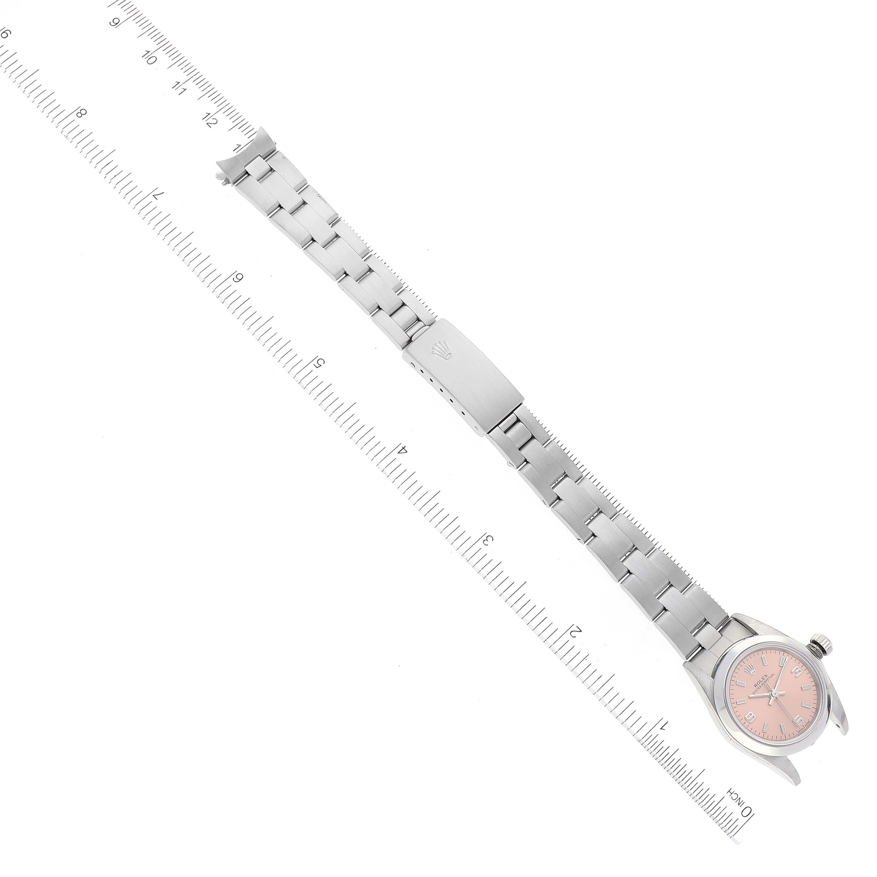 This image shows an overhead view of a Rolex Oyster Perpetual 76080 Women
s Stainless Steel Pink Dial 76080 Women
s Stainless Steel Pink Dial watch with stainless steel bracelet aligned along a ruler.
