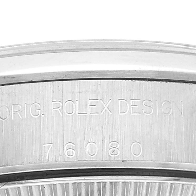 This image shows a close-up of the side of the bezel and case of a Rolex Oyster Perpetual 76080 Women
s Stainless Steel Pink Dial 76080 Women
s Stainless Steel Pink Dial watch, featuring the engraved model number and "ORIG. ROLEX DESIGN".