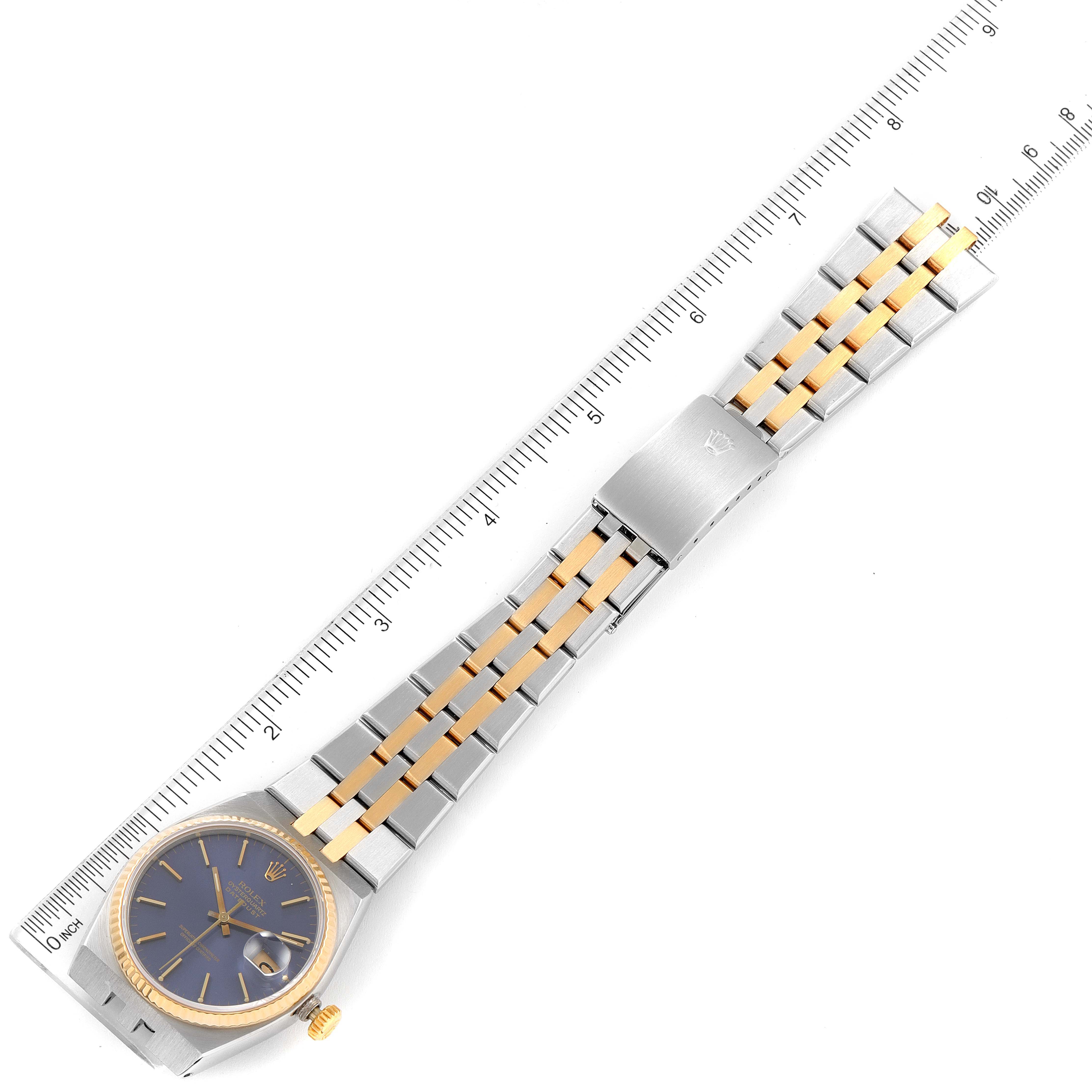 The Rolex Oysterquartz 17013 Men's Steel and Gold (two tone) Blue Dial 17013 Men's Steel and Gold (two tone) Blue Dial is shown in a top view, displaying the watch face, bracelet, and clasp alongside a ruler for scale.