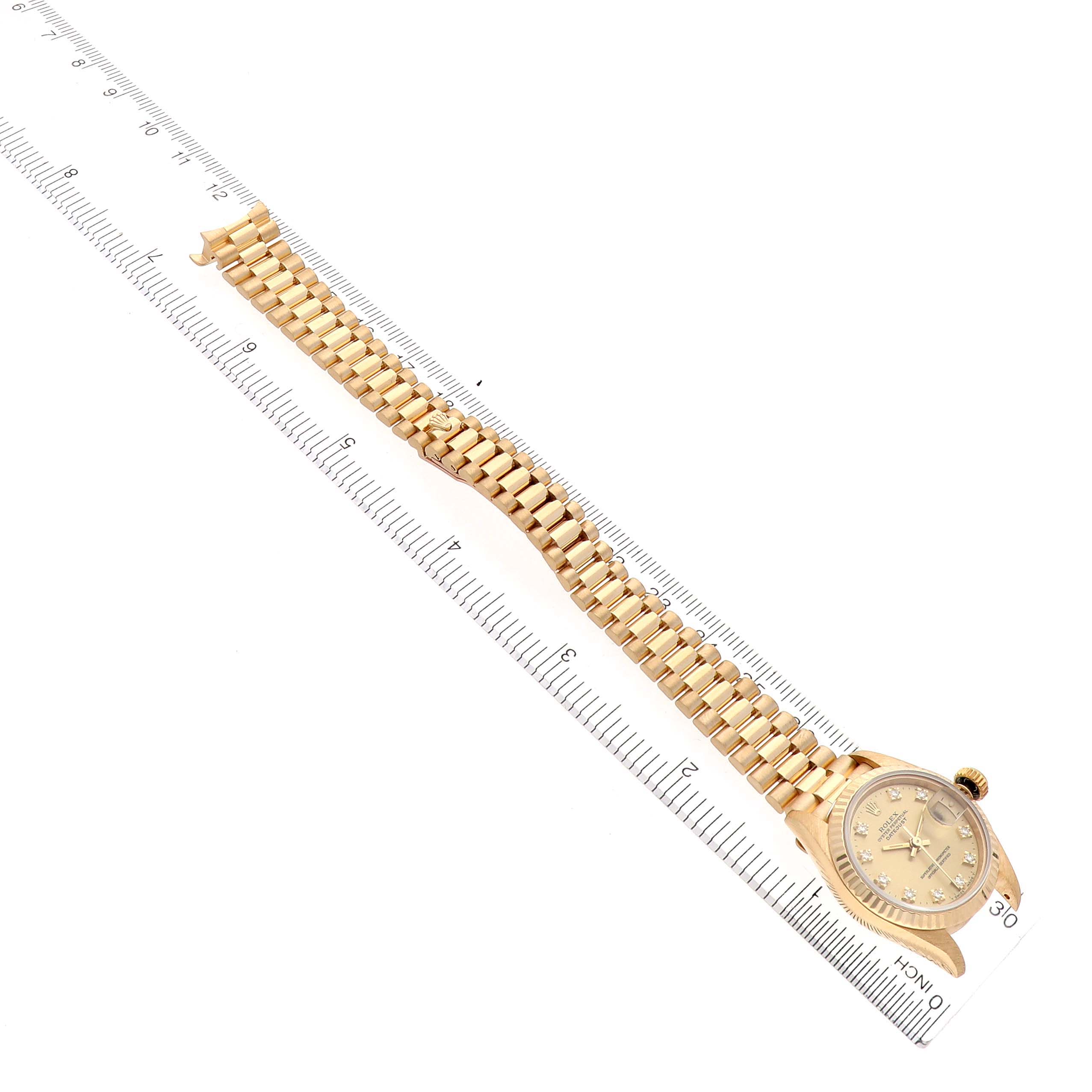 The Rolex President 69178 Women's Yellow Gold Champagne Dial 69178 Women's Yellow Gold Champagne Dial watch is shown at an angle, displaying the gold bracelet and face, aligned alongside a ruler.