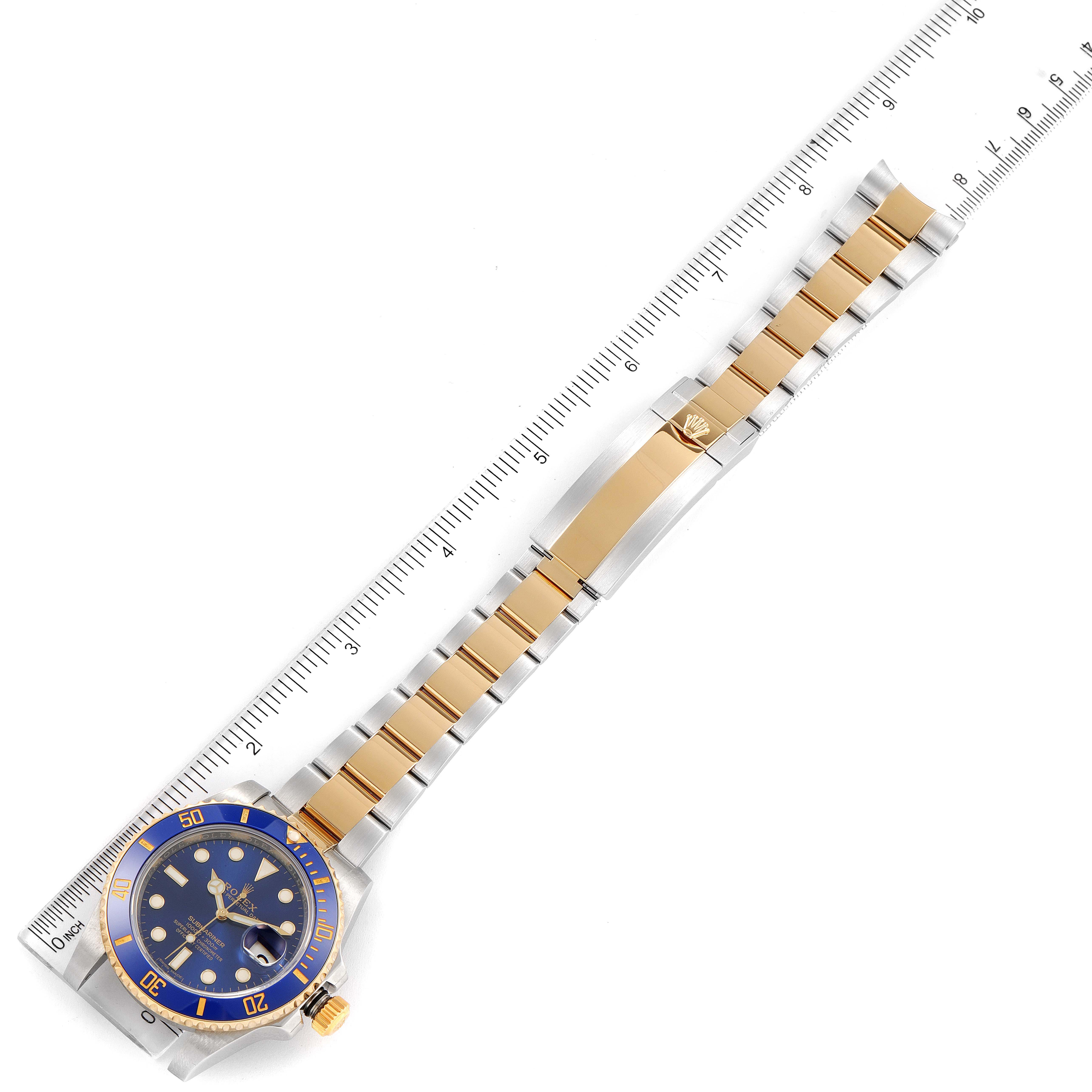 This image shows a Rolex Submariner 116613 Men's Steel and Gold (two tone) Blue Dial 116613 Men's Steel and Gold (two tone) Blue Dial watch laid flat with a ruler, highlighting the band and face.