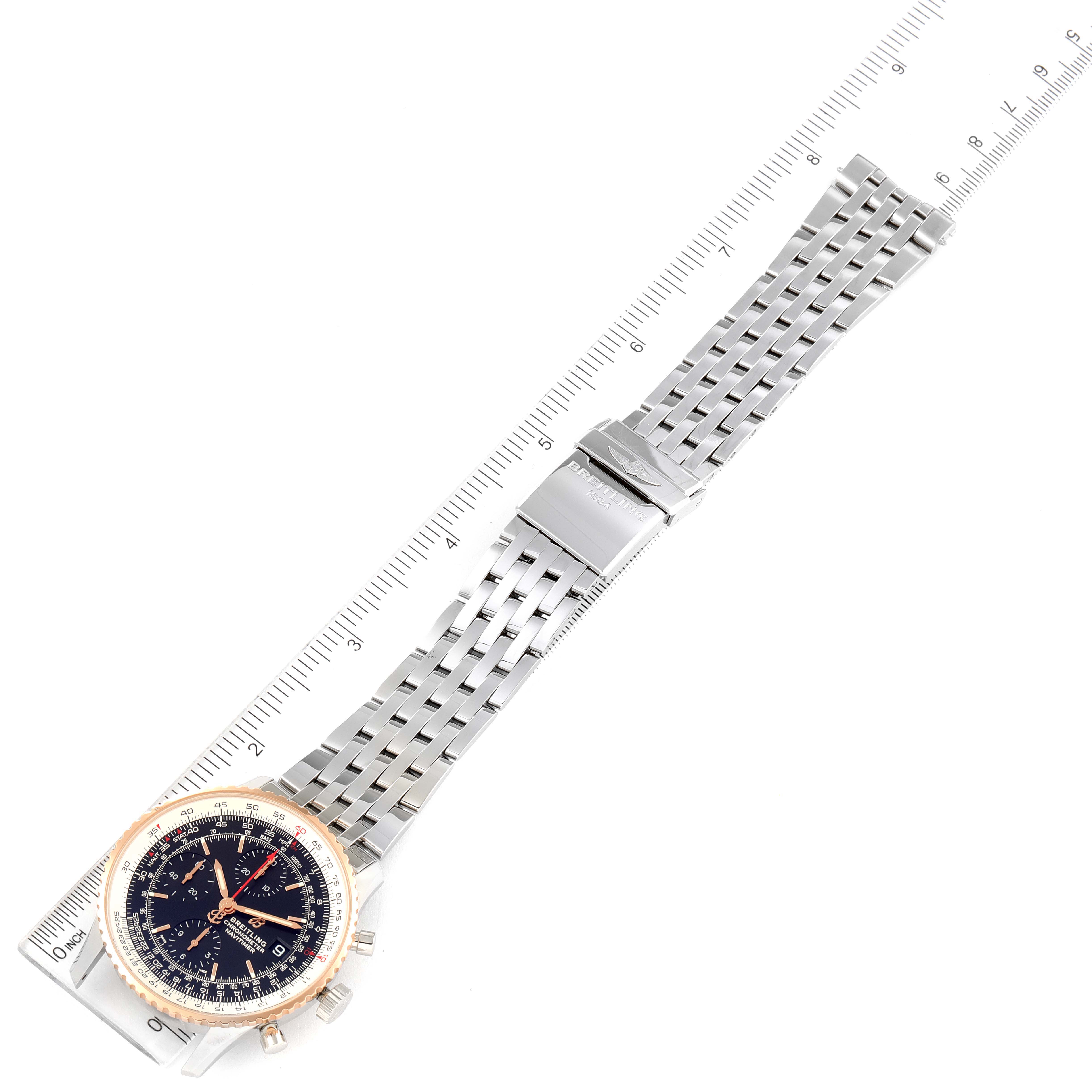 The image shows a Breitling Navitimer U13324211B1X1 Men's Steel and Gold (two tone) Black Dial U13324211B1X1 Men's Steel and Gold (two tone) Black Dial watch laid flat, showcasing its metallic strap and clasp, with a ruler for scale.