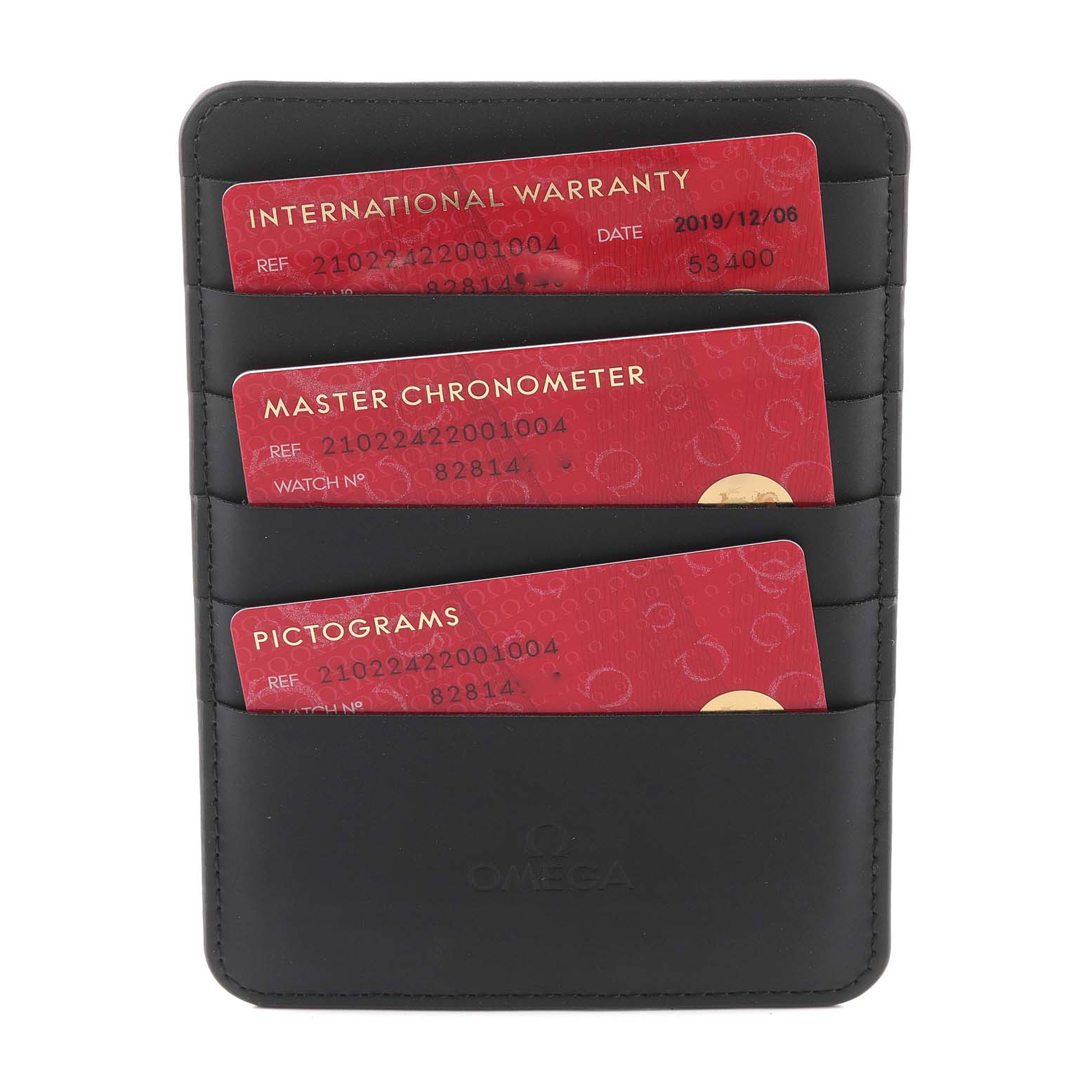 This image shows three red cards (International Warranty, Master Chronometer, and Pictograms) in a black Omega cardholder for a Seamaster model.
