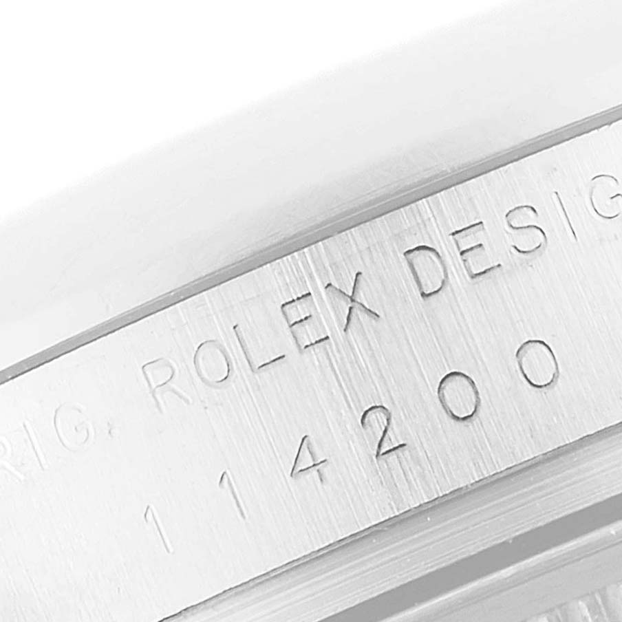 The image shows a close-up of the serial number engraving on a Rolex Air-King 114200 Men's Stainless Steel Silver Dial 114200 Men's Stainless Steel Silver Dial watch case.