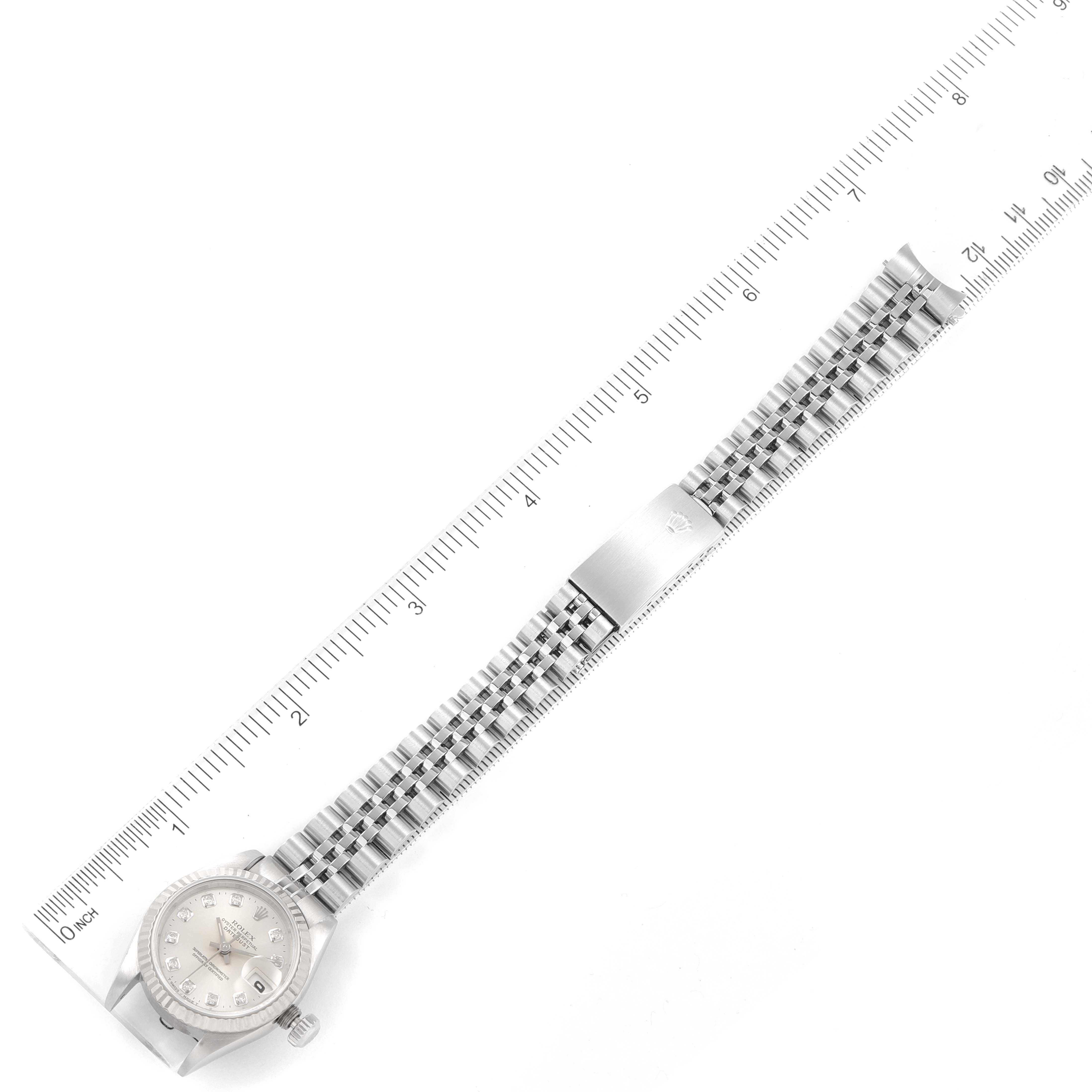 The Rolex Datejust 69174 Women
s Stainless Steel Silver Dial 69174 Women
s Stainless Steel Silver Dial watch is shown from a top-down angle, displaying the face, bezel, and bracelet against a ruler for scale.