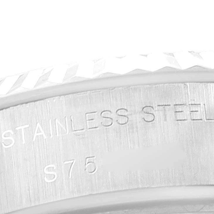 The image shows a close-up of the side of a Rolex Datejust 69174 Women
s Stainless Steel Silver Dial 69174 Women
s Stainless Steel Silver Dial model watch, featuring its fluted bezel and "STAINLESS STEEL" inscription.