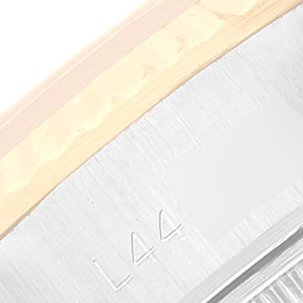 This close-up image shows the side portion of a Rolex Datejust 69173 Women's Steel and Gold (two tone) Champagne Dial 69173 Women's Steel and Gold (two tone) Champagne Dial watch, specifically the bezel and part of the case with an engraving.