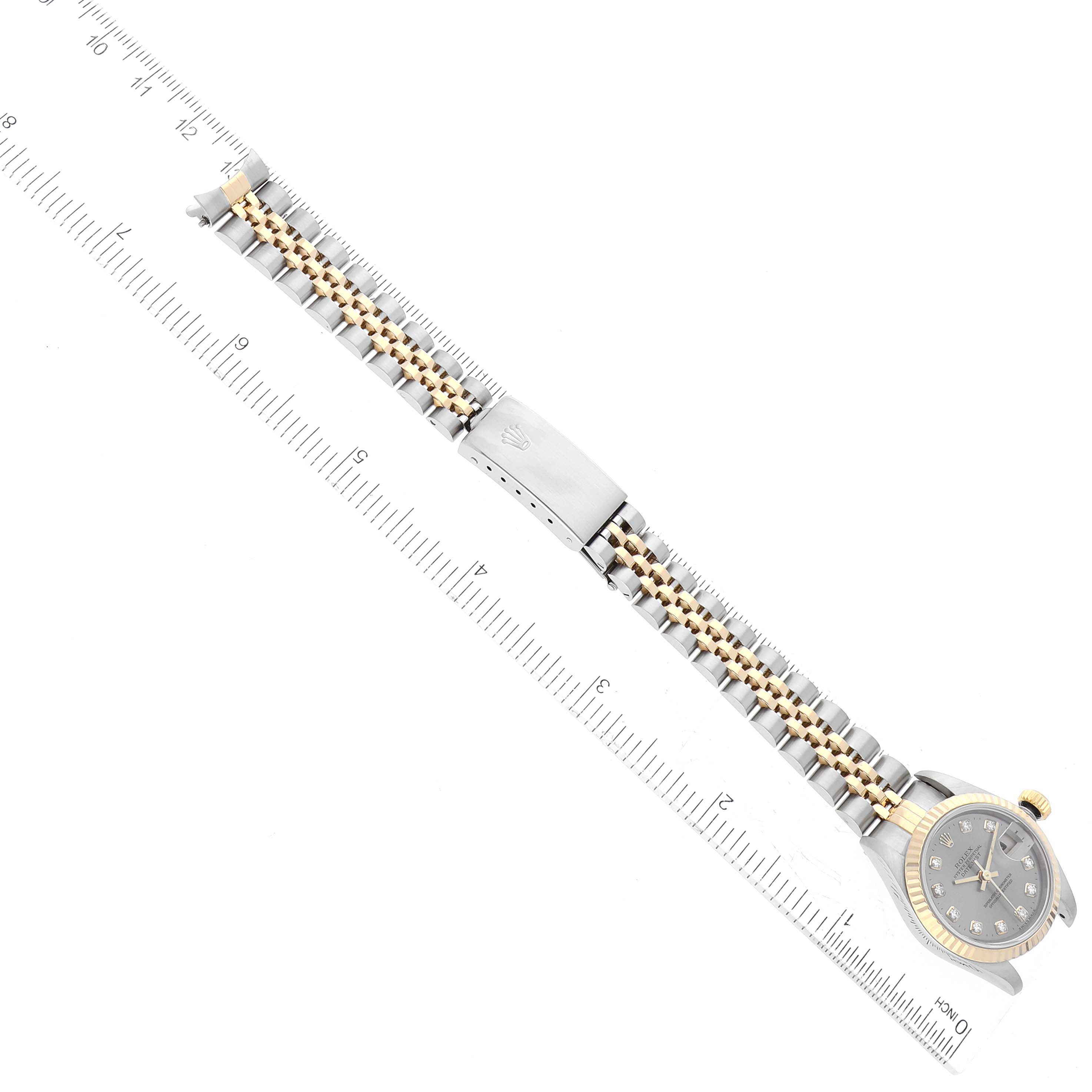 The image shows a top-down view of a Rolex Datejust 79173G Women's Steel and Gold (two tone) Grey Dial 79173G Women's Steel and Gold (two tone) Grey Dial watch with its band and clasp alongside a ruler for scale.