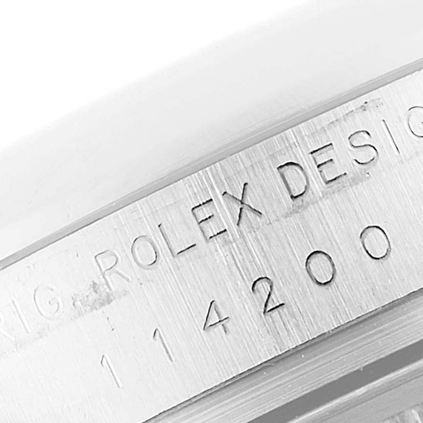 This image shows a close-up of the serial and model number engraving on the case side of a Rolex Oyster Perpetual 114200 Men's Stainless Steel Black Dial 114200 Men's Stainless Steel Black Dial watch.