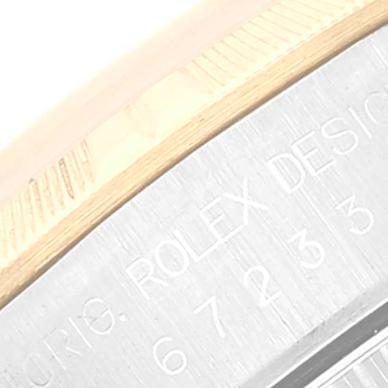 This image shows a close-up of the bezel and part of the engraved text from a Rolex Oyster Perpetual 67233 Women's Steel and Gold (two tone) Silver Dial 67233 Women's Steel and Gold (two tone) Silver Dial watch.