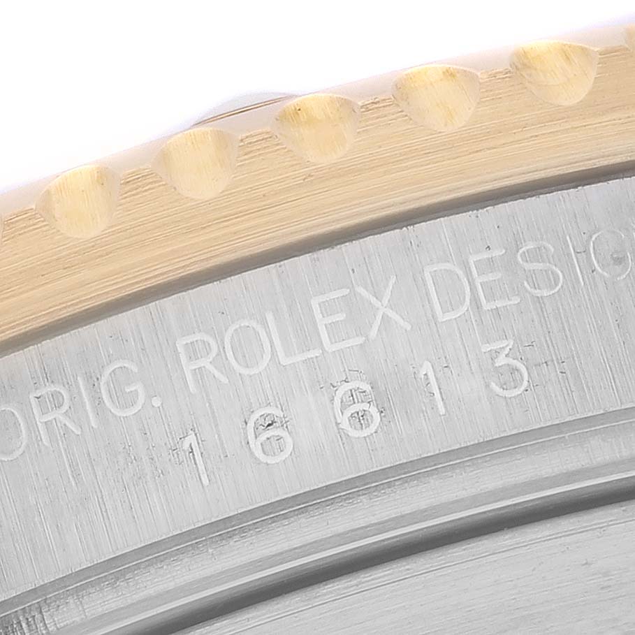 The image shows a close-up of the Rolex Submariner 16613 Men's Steel and Gold (two tone) Blue Dial 16613 Men's Steel and Gold (two tone) Blue Dial's bezel and part of the engraved case with the model number 16613.
