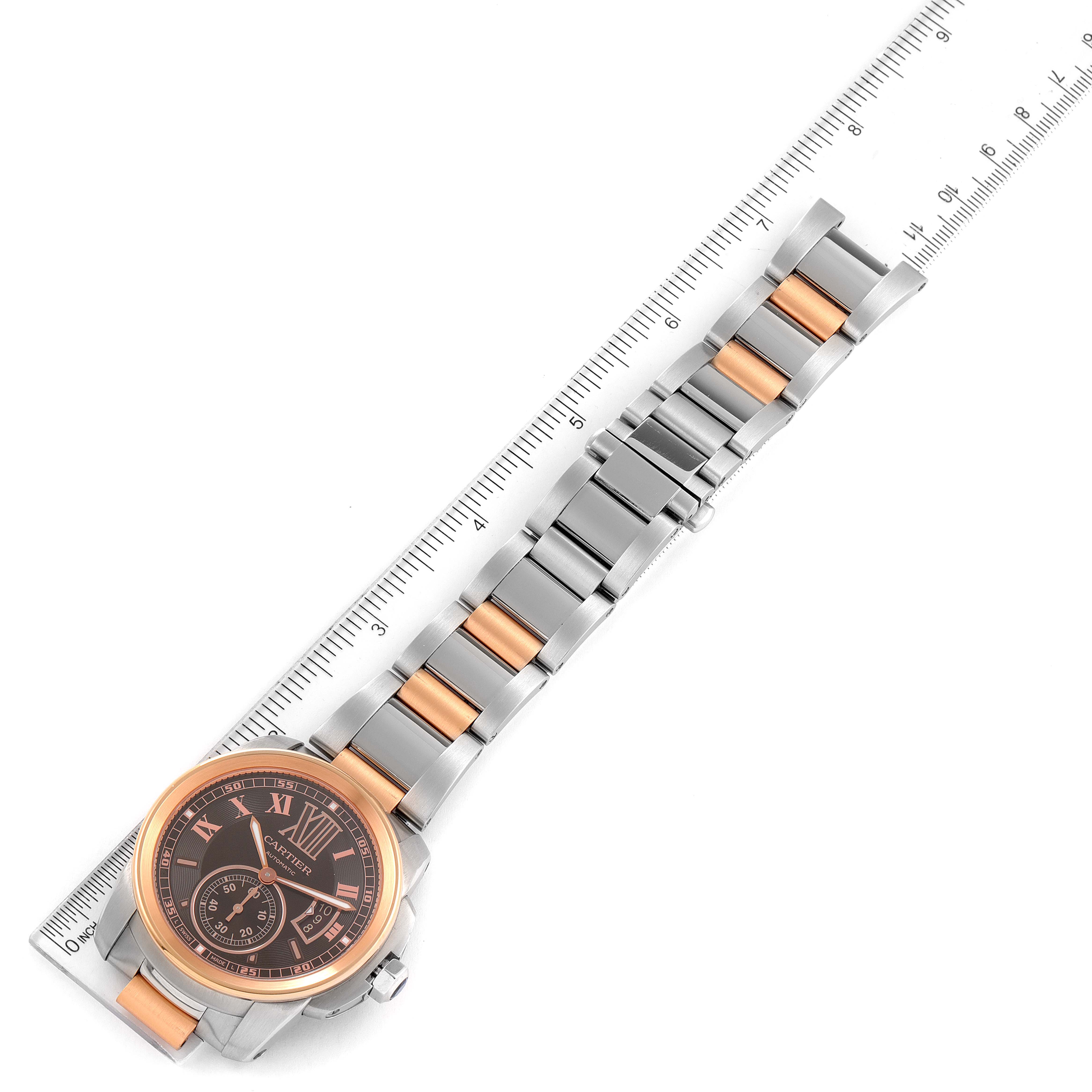 The image shows a top-down view of a Calibre de Cartier watch by Cartier with its band aligned against a ruler.