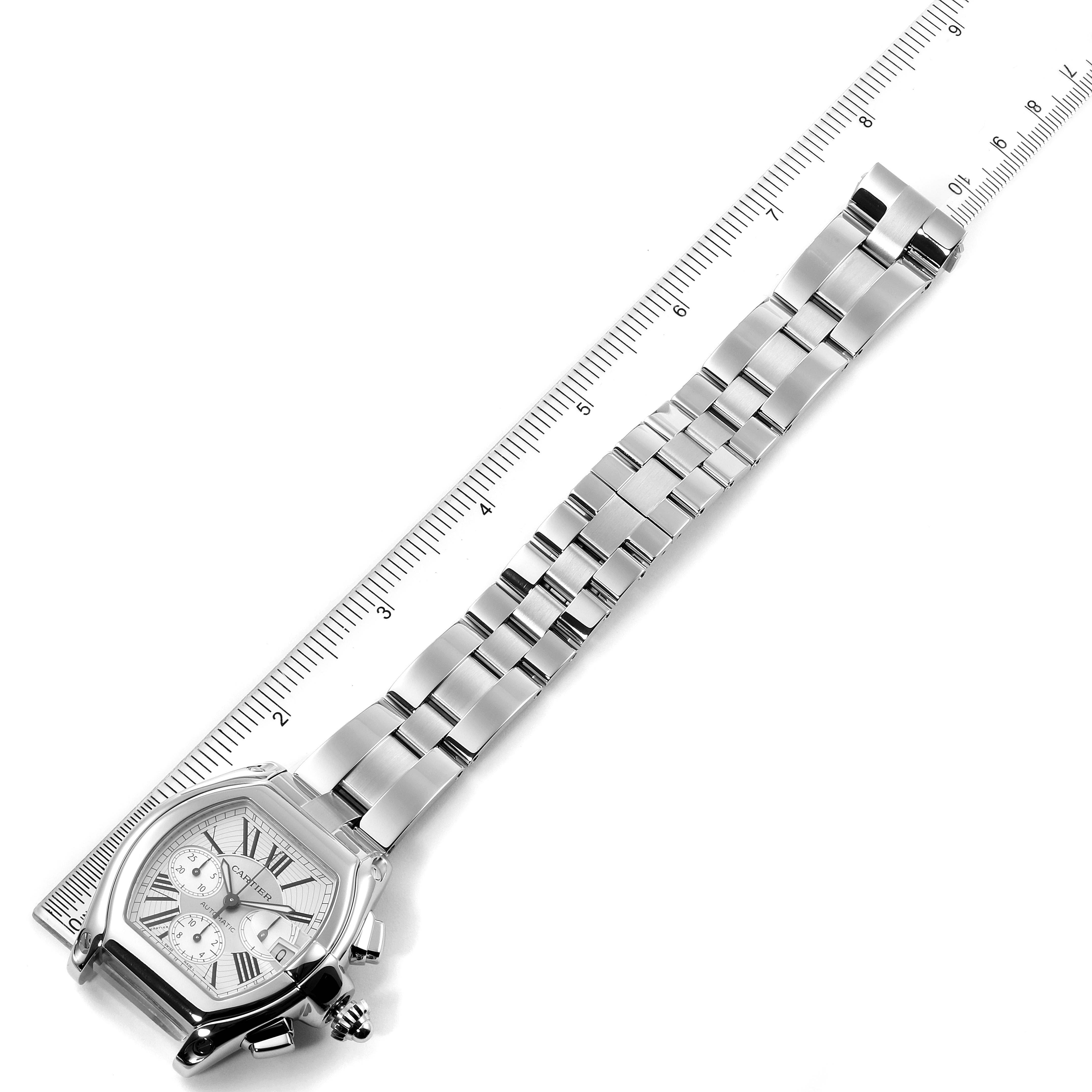 The image shows a Cartier Roadster W62019X6 Men's Stainless Steel Silver Dial W62019X6 Men's Stainless Steel Silver Dial watch laid flat with a ruler beside it, displaying the face and metal bracelet.