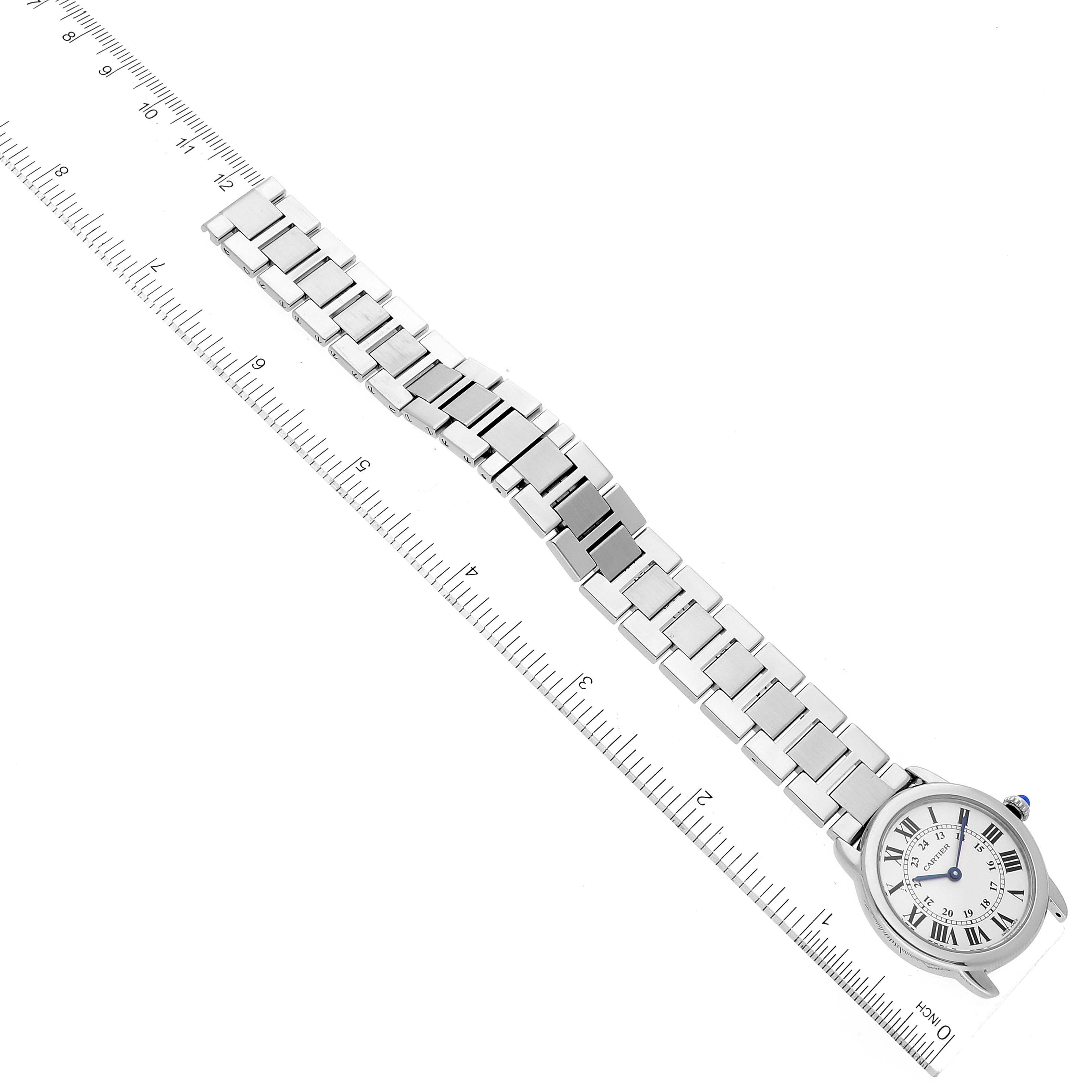 The image shows a top-down view of a Cartier Ronde W6701004 Women's Stainless Steel Silver Dial W6701004 Women's Stainless Steel Silver Dial watch with a metal bracelet and a ruler for scale.