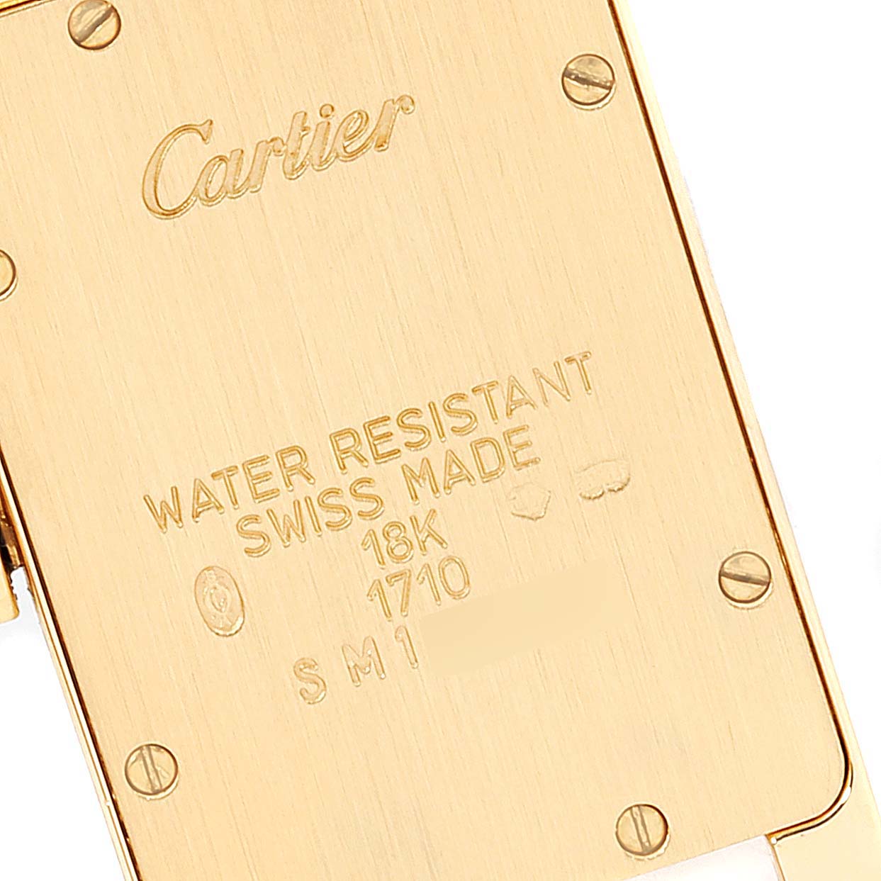 This image shows the back case of the Cartier Tank Américaine watch, displaying its engravings and screws.