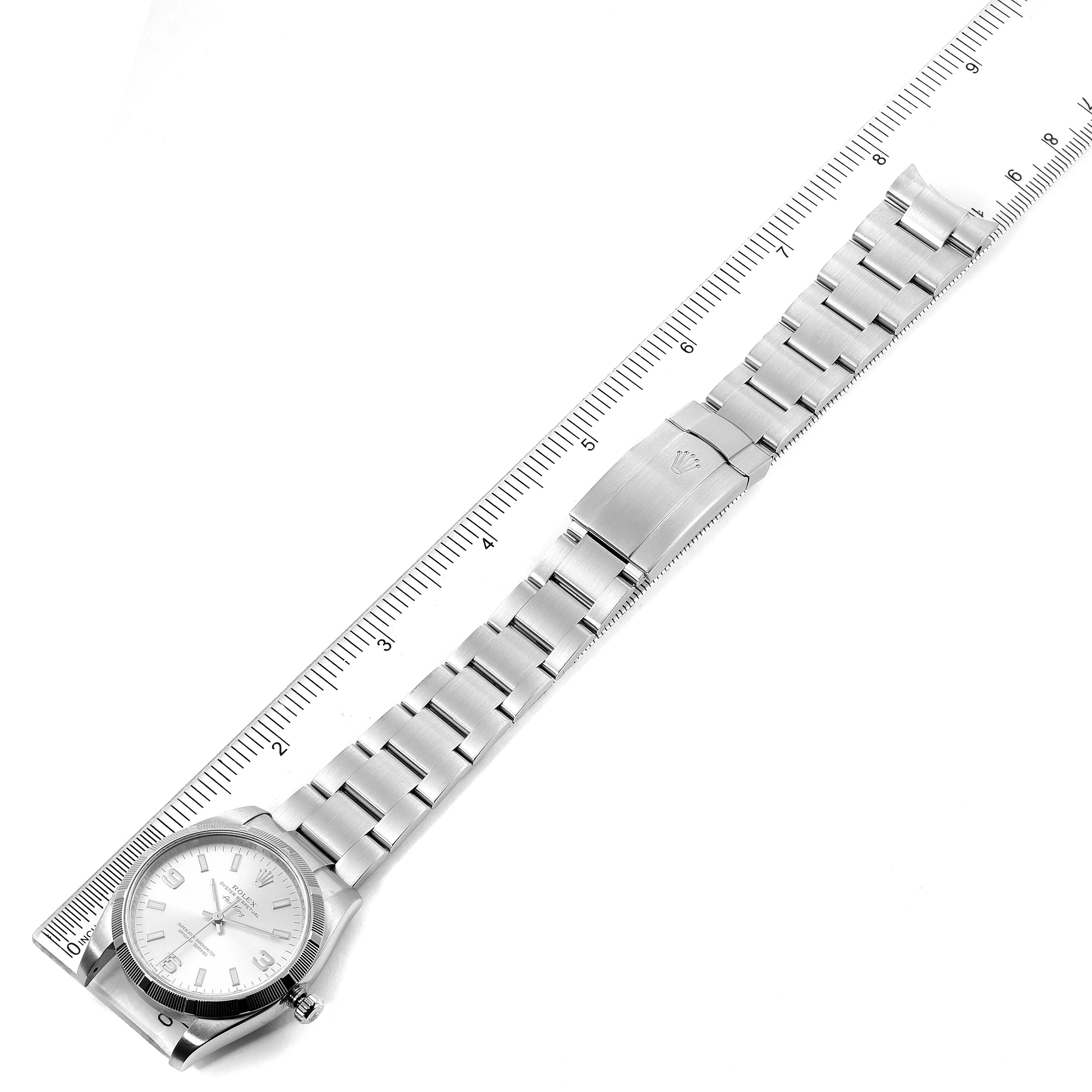 The image shows a top-down view of a Rolex Air-King 114210 Men's Stainless Steel Silver Dial 114210 Men's Stainless Steel Silver Dial watch with a full metal bracelet next to a ruler for scale.