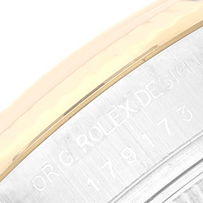 The image shows a close-up of the side of a Rolex Datejust 179173 Women's Steel and Gold (two tone) Champagne Dial 179173 Women's Steel and Gold (two tone) Champagne Dial watch, highlighting part of the bezel and engraved text.