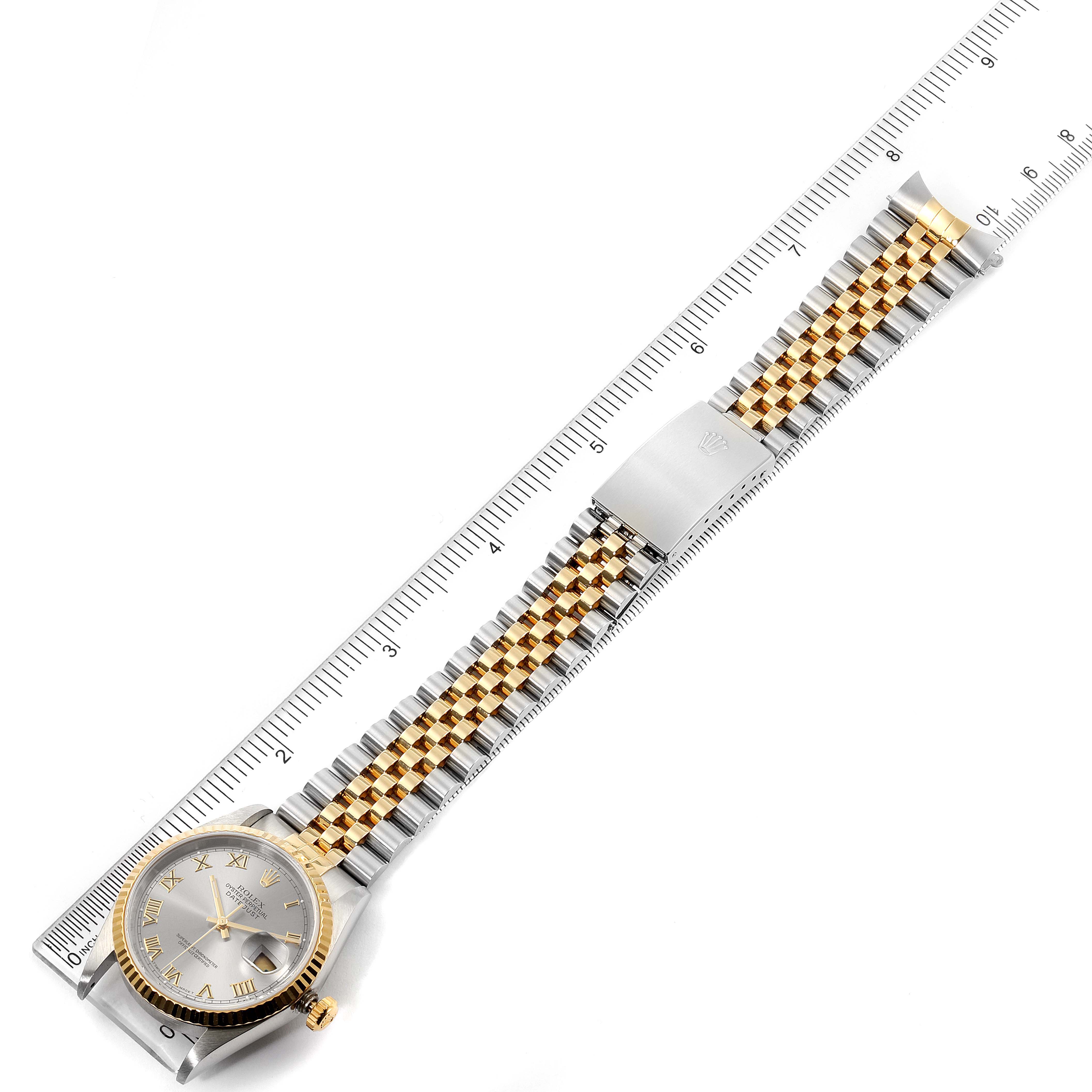 The image shows a full frontal view of a Rolex Datejust 16233 Men
s Steel and Gold (two tone) Grey Dial 16233 Men
s Steel and Gold (two tone) Grey Dial watch, including its dial, bracelet, and clasp, placed next to a ruler.
