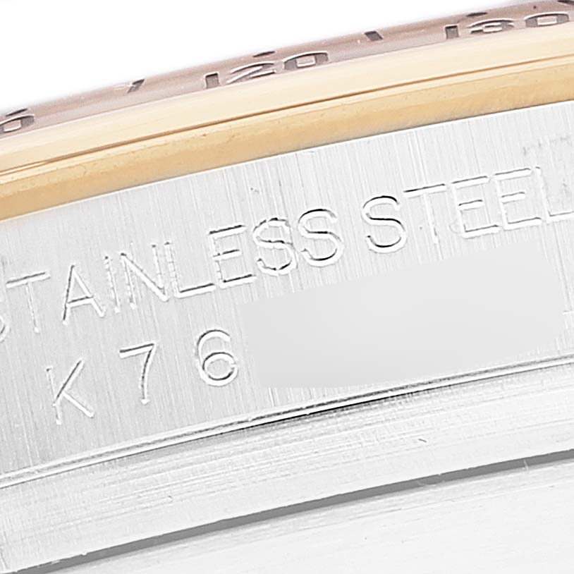 The image shows a close-up of the edge of a Rolex Daytona 116523 Men's Steel and Gold (two tone) Black Dial 116523 Men's Steel and Gold (two tone) Black Dial watch, focusing on the stainless steel case with partial bezel and engravings visible.