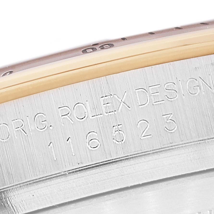 The close-up image shows the engraved model number and "ORIG. ROLEX DESIGN" text on the side of a Rolex Daytona 116523 Men's Steel and Gold (two tone) Black Dial 116523 Men's Steel and Gold (two tone) Black Dial watch.