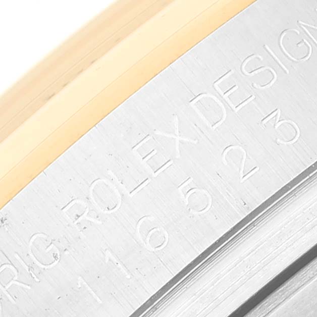 The image shows a close-up of the bezel and casing of a Rolex Daytona 116523 Men's Steel and Gold (two tone) Mother of Pearl Dial 116523 Men's Steel and Gold (two tone) Mother of Pearl Dial watch, featuring engraved text.