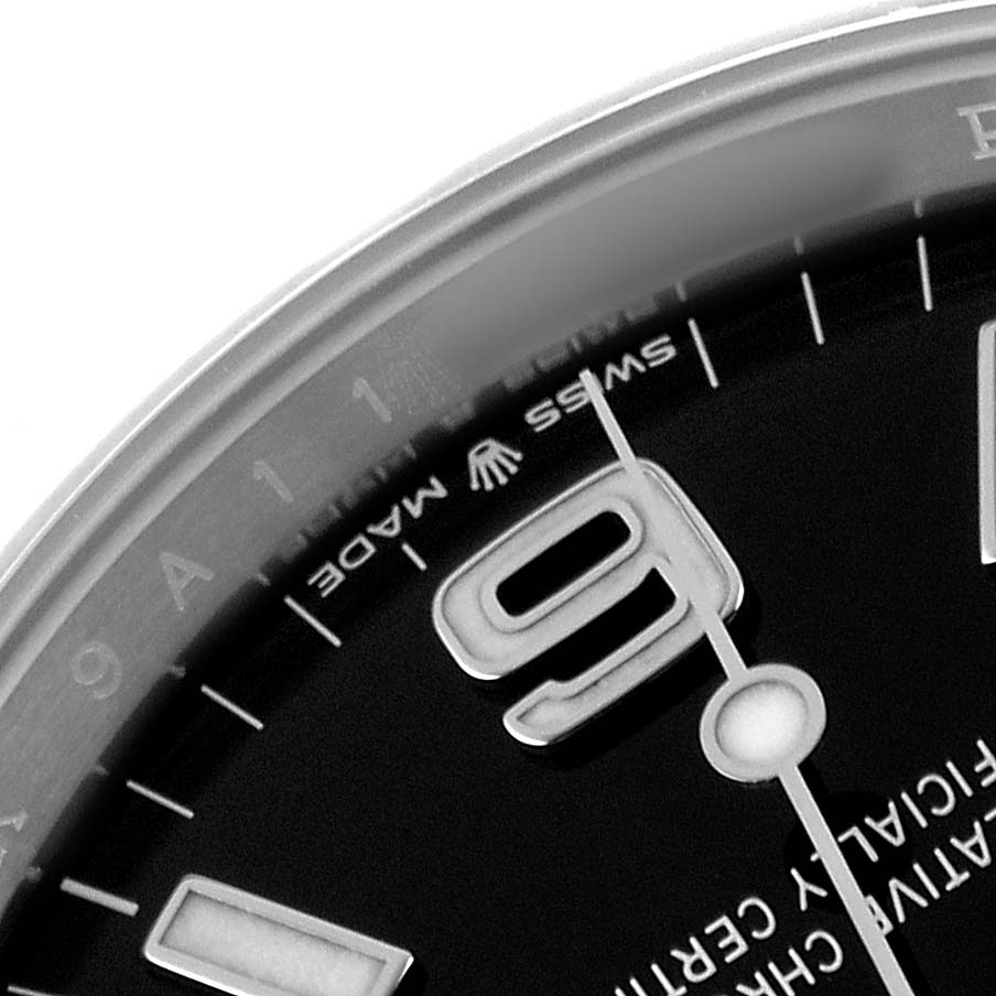 The image shows a close-up of the dial of a Rolex Explorer 124270 Men's Stainless Steel Black Dial watch, featuring part of the bezel, hour markers, and branding.