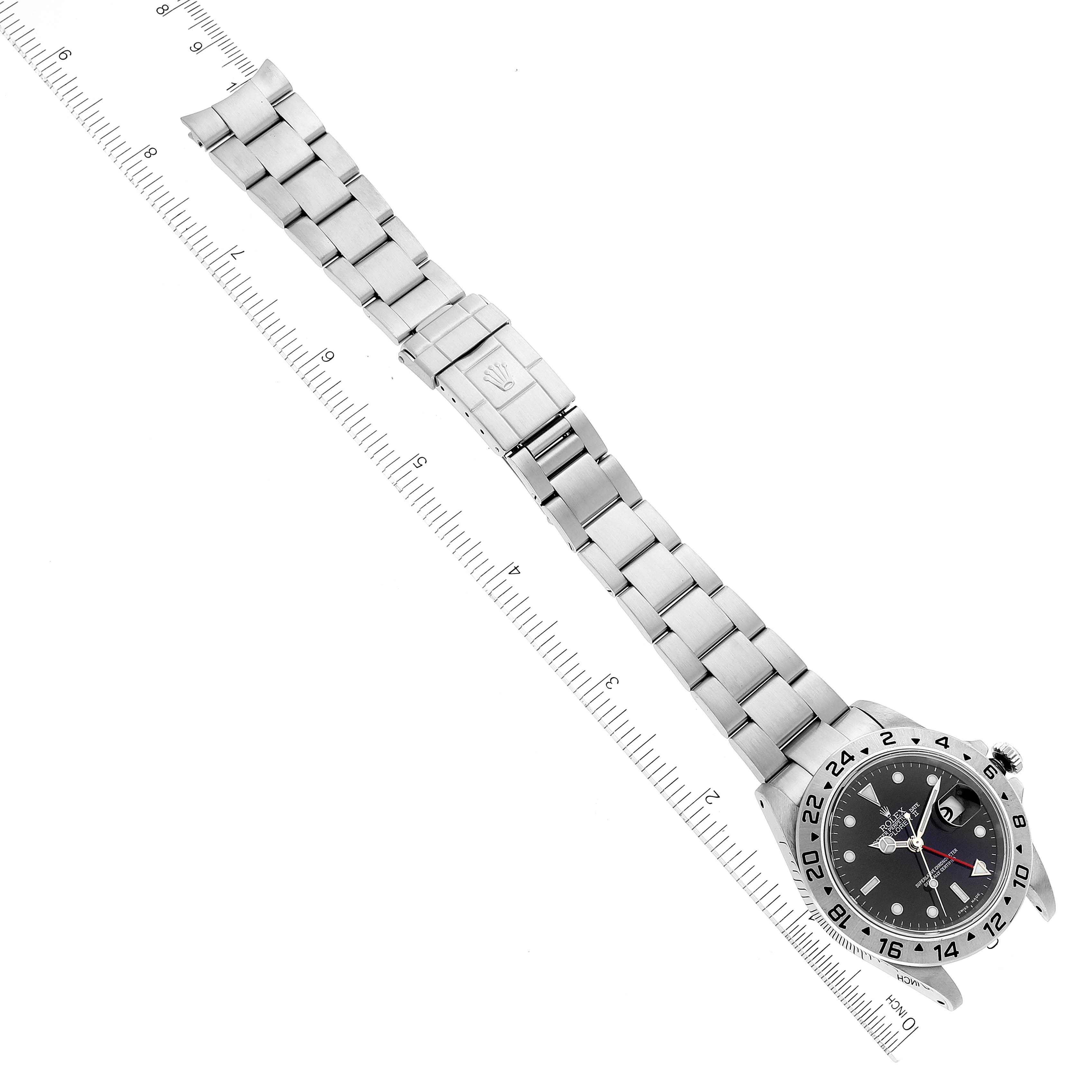 The image shows a Rolex Explorer 16570 Men
s Stainless Steel Black Dial 16570 Men
s Stainless Steel Black Dial watch laid flat with its band extended alongside a ruler displaying both centimeters and inches.