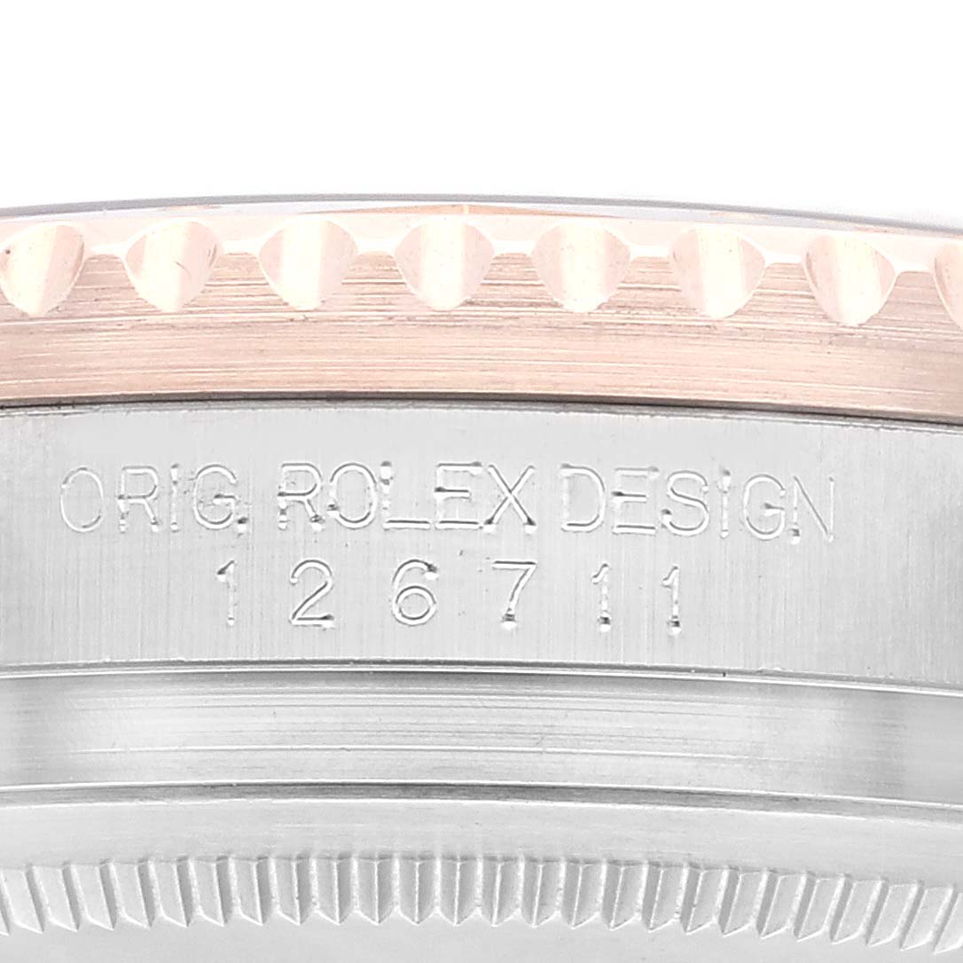 The image shows a close-up view of the Rolex GMT-Master 126711CHNR Men's Steel and Gold (two tone) Black Dial 126711CHNR Men's Steel and Gold (two tone) Black Dial model's case with engravings of "ORIG. ROLEX DESIGN" and model number "126711."