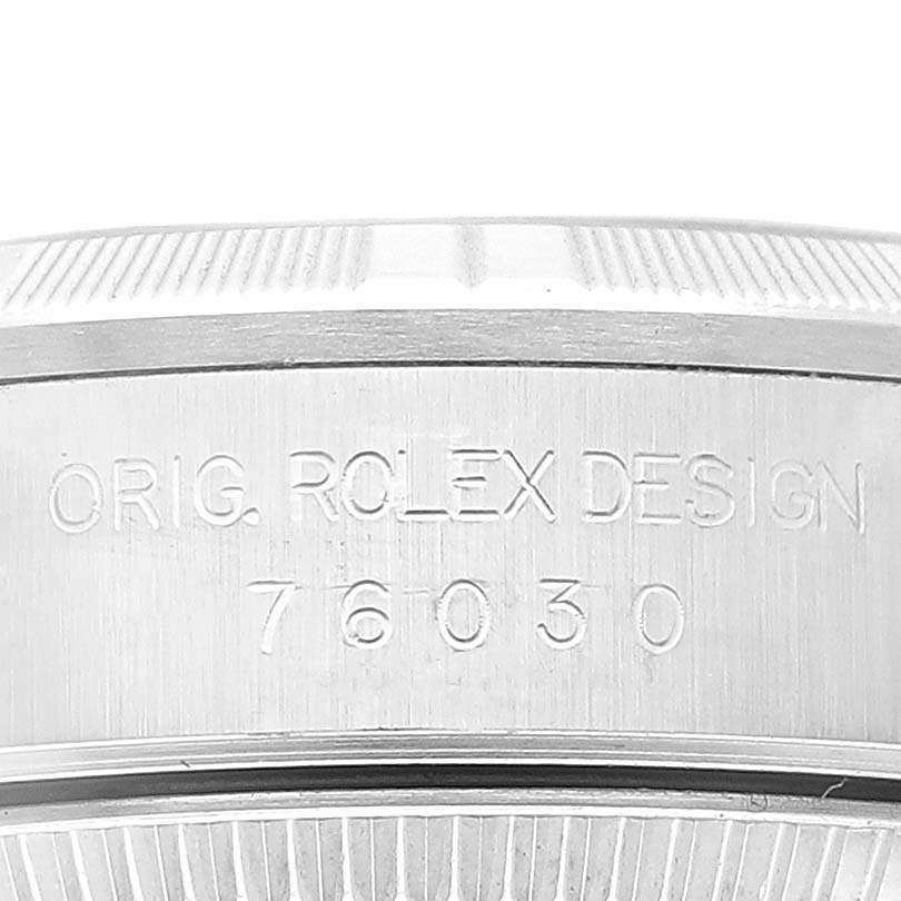 The image shows a close-up view of the side of a Rolex Oyster Perpetual 76030 Women's Stainless Steel Orange Dial 76030 Women's Stainless Steel Orange Dial watch, highlighting the engraved model number and branding.