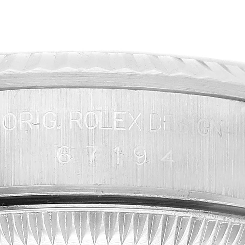 This close-up shows the engraved side of the casing of a Rolex Oyster Perpetual 67194 Women's Stainless Steel Orange Dial 67194 Women's Stainless Steel Orange Dial watch.