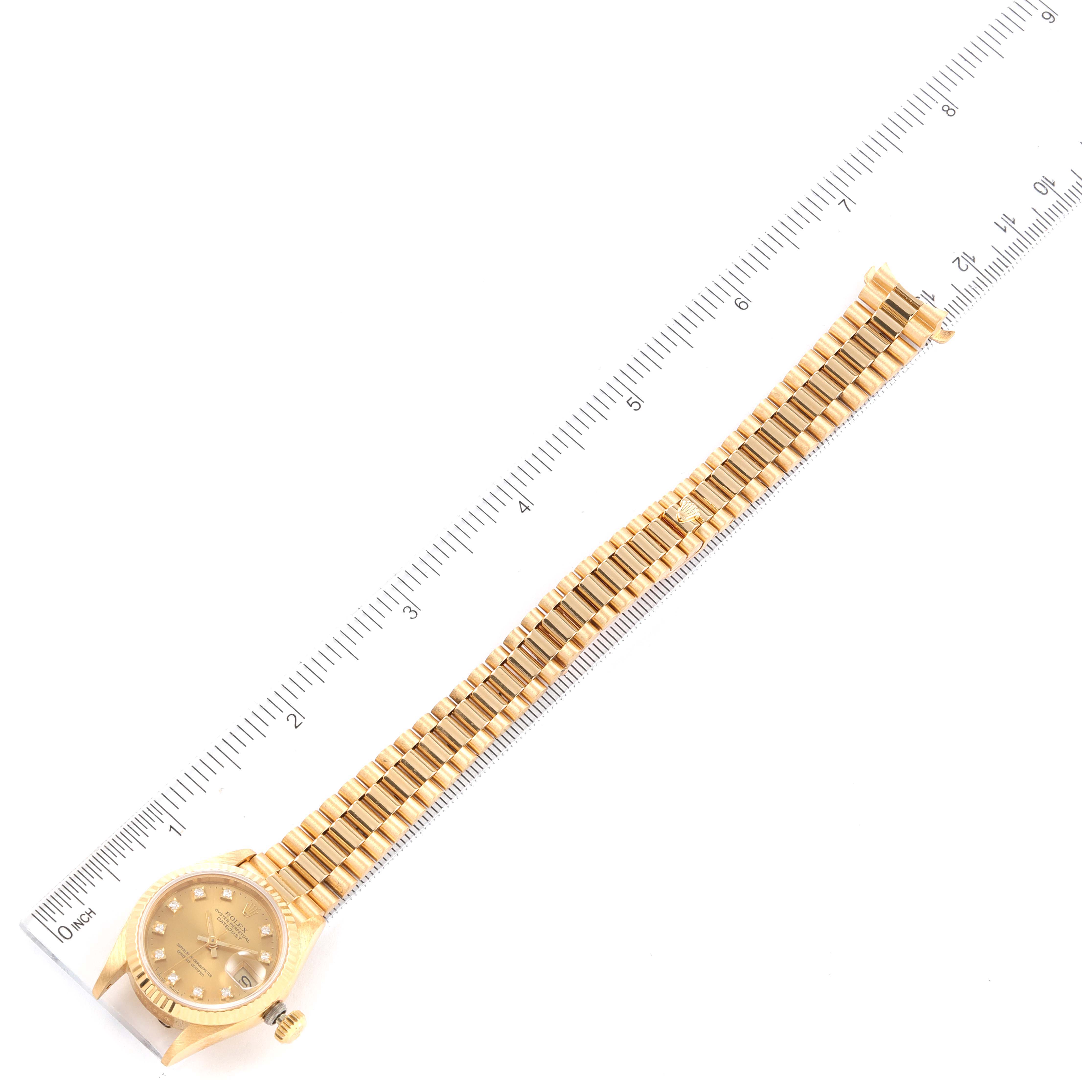 The image shows an overhead view of a Rolex President 69178 Women's Yellow Gold Champagne Dial 69178 Women's Yellow Gold Champagne Dial model watch, displaying its case, dial, bracelet, and a measuring ruler.