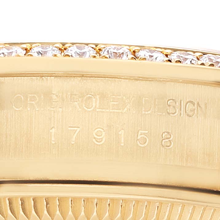 The image shows a close-up of the engraved case of a Rolex President 179158 Women's Yellow Gold Champagne Dial 179158 Women's Yellow Gold Champagne Dial model, highlighting the serial number and a diamond-studded bezel.