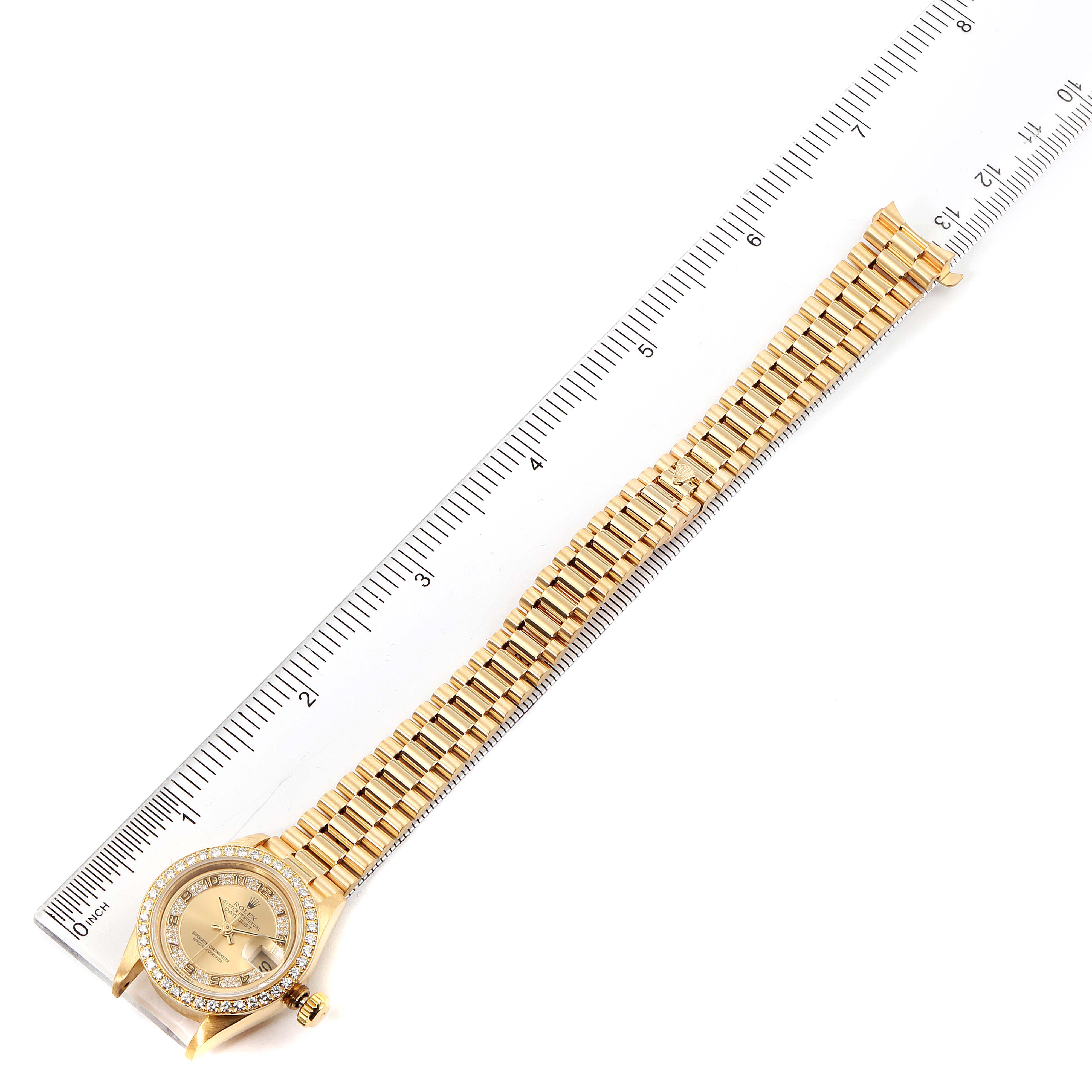 The image shows a Rolex President 69178 Women
s Yellow Gold Champagne Dial 69178 Women
s Yellow Gold Champagne Dial model watch lying flat with its full band and face visible next to a ruler for scale.