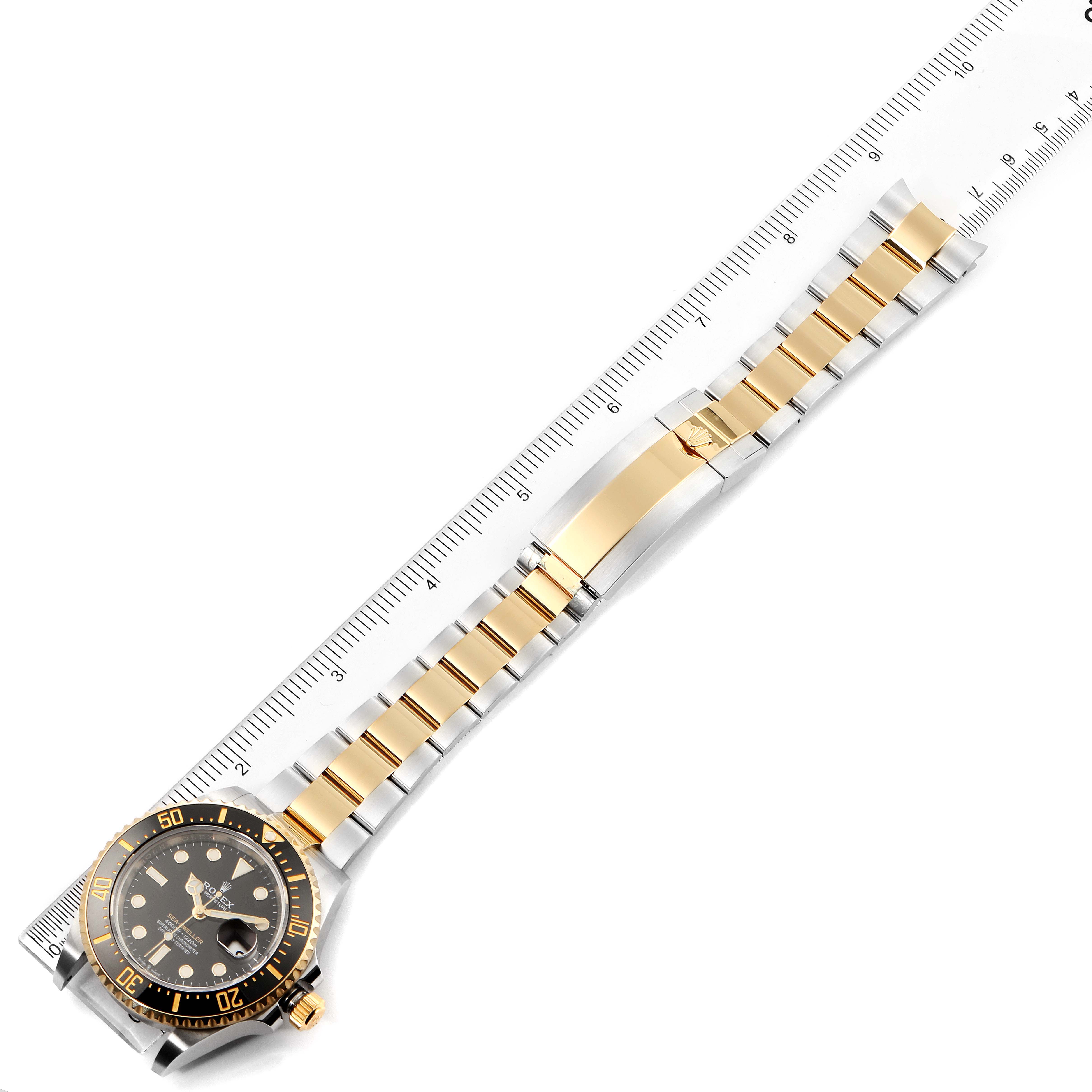 The image shows the Rolex Sea-Dweller 126603 Men
s Steel and Gold (two tone) Black Dial 126603 Men
s Steel and Gold (two tone) Black Dial watch laid flat, highlighting both the face and entire metal link bracelet, with a ruler for scale.