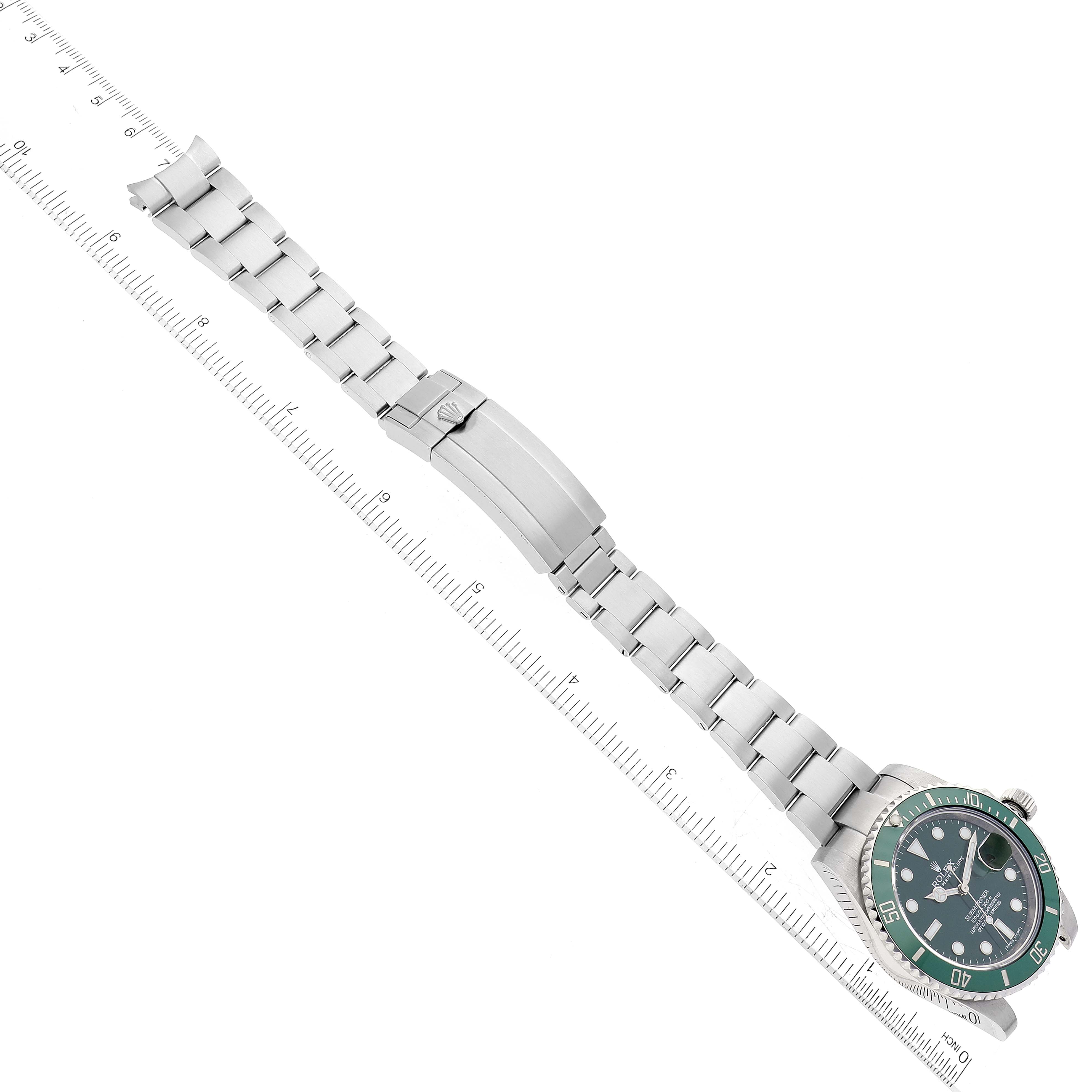 The image shows a Rolex Submariner 116610LV Men's Stainless Steel Green Dial 116610LV Men's Stainless Steel Green Dial watch with its full stainless steel bracelet positioned diagonally along a ruler.