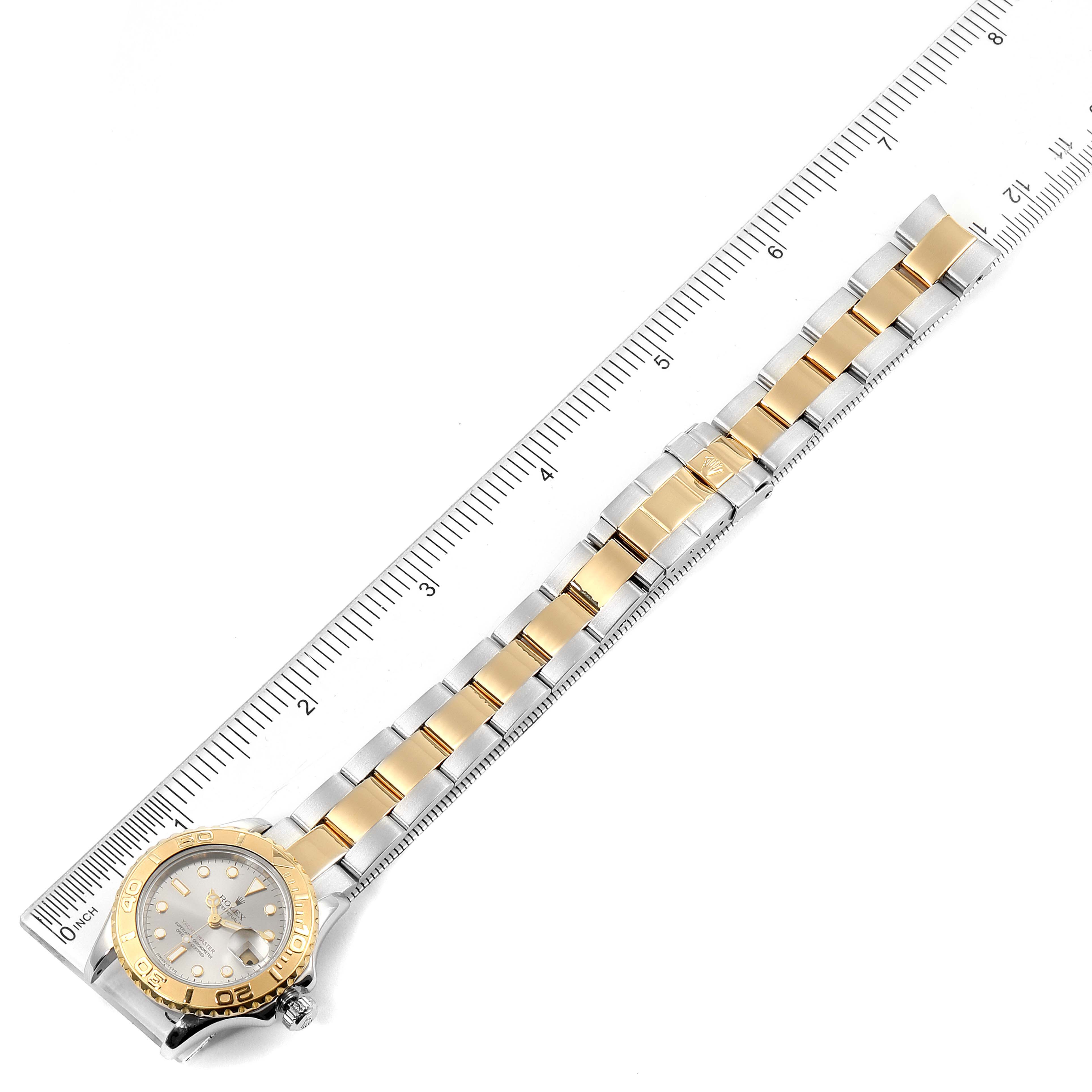 The image shows a top-down view of a Rolex Yacht-Master 169623 Women's Steel and Gold (two tone) Grey Dial 169623 Women's Steel and Gold (two tone) Grey Dial watch, including its face, bezel, and two-tone bracelet next to a ruler for scale.